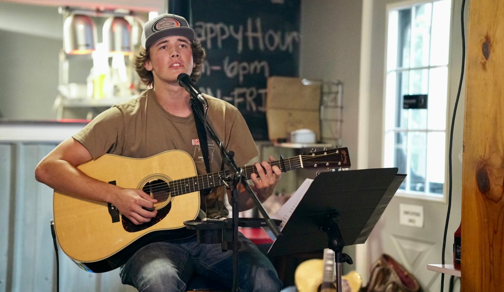 Mickey Hettwer tip jar: a young man playing an acoustic guitar in a bar