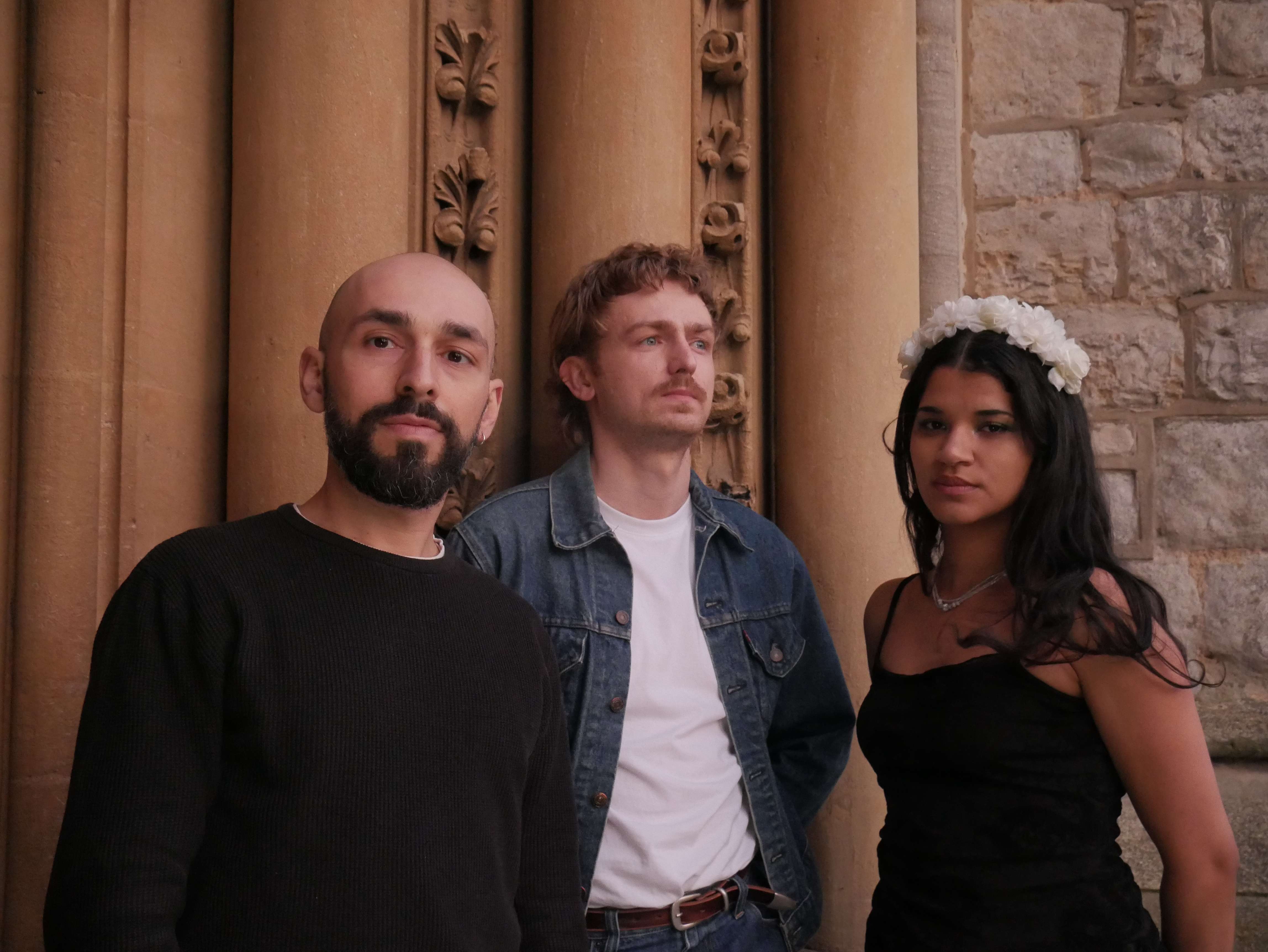 three people posing in front of a stone building
