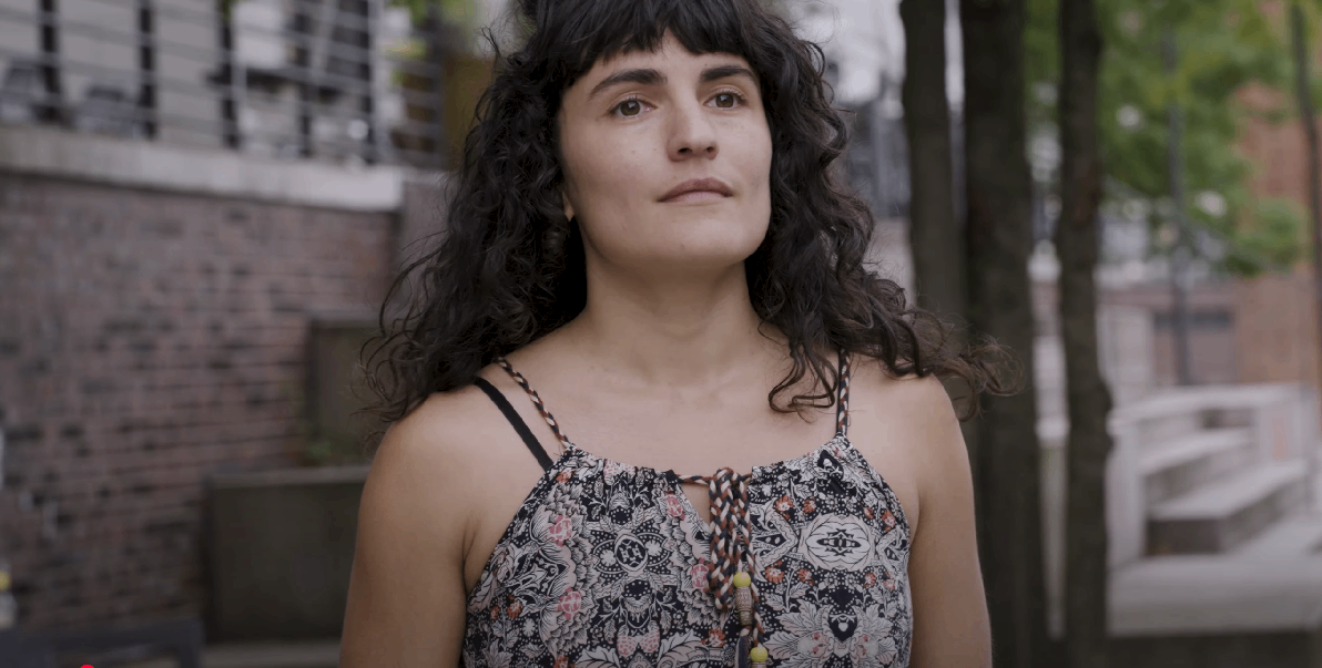a woman in a floral top is standing on a sidewalk