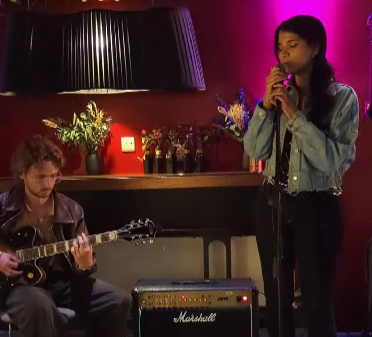 two people singing and playing guitar in a room