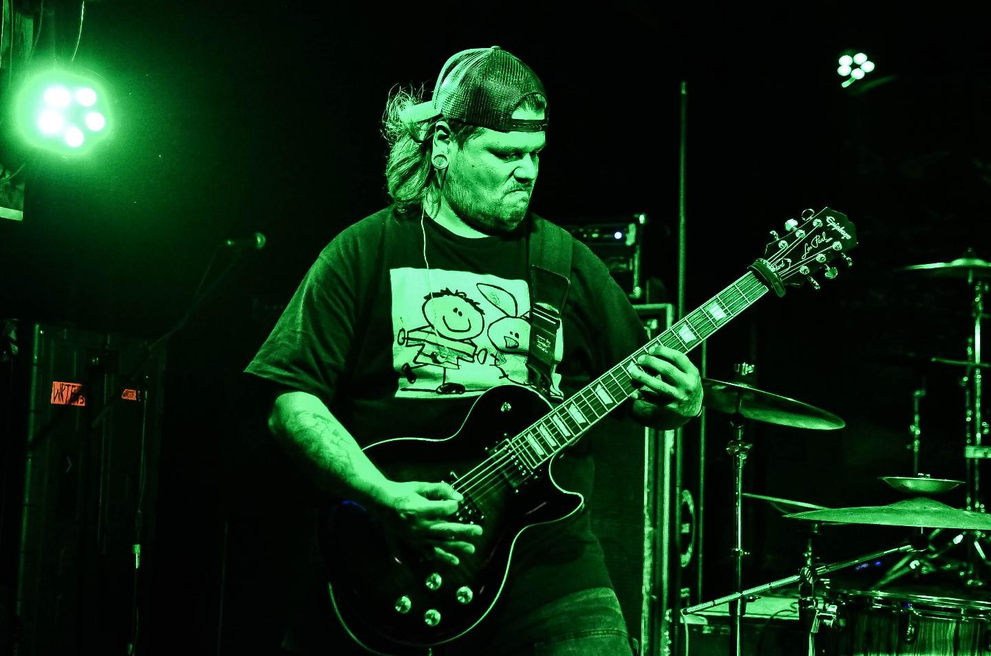 a man playing a guitar in front of a green light
