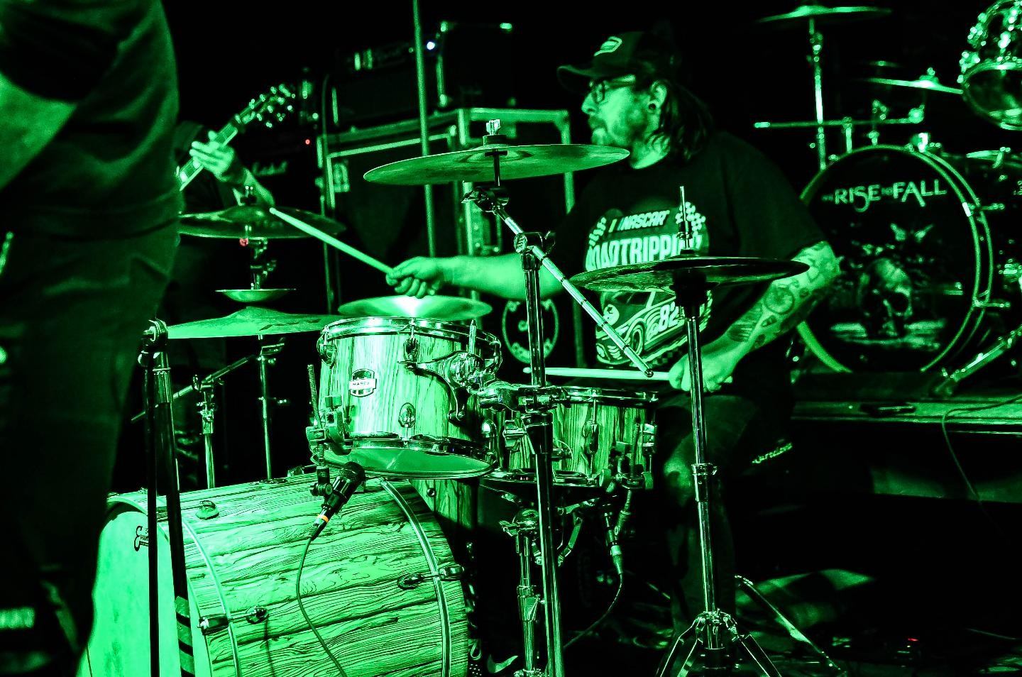 a band playing drums on stage in a green light