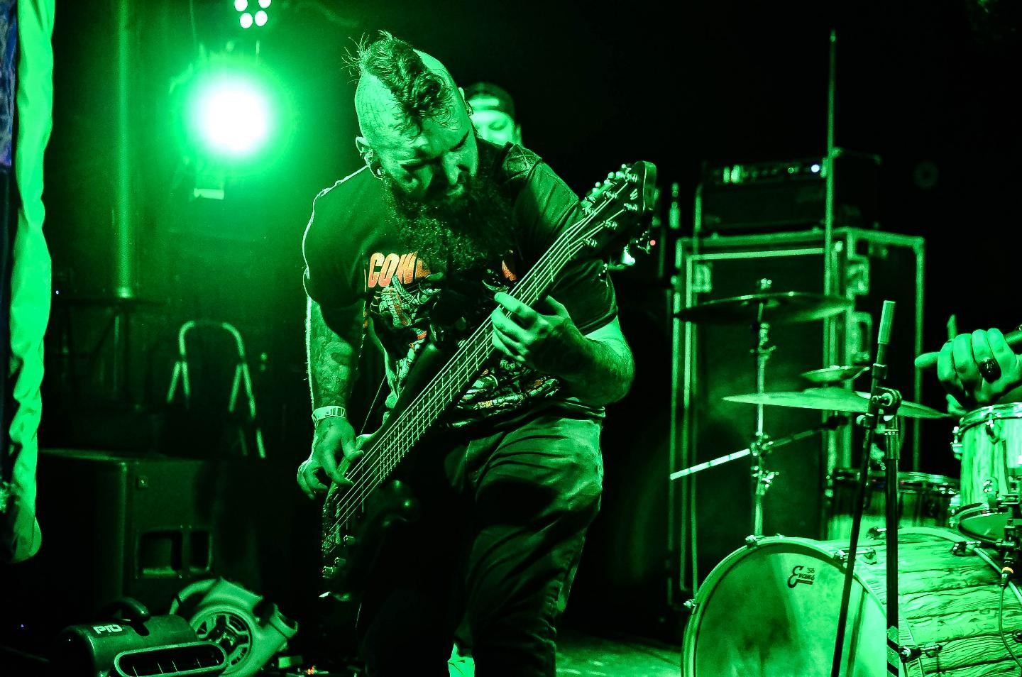 a man playing a bass in front of a green light