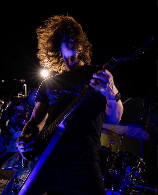a man with long hair playing an electric guitar