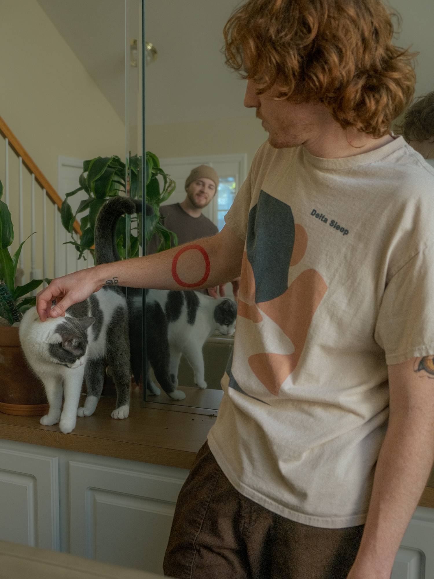 a man petting a cat in front of a mirror