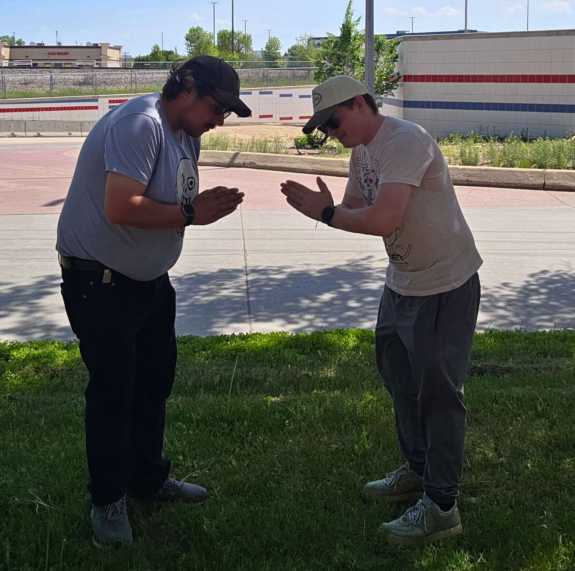two men standing in a grassy area looking at a cell phone
