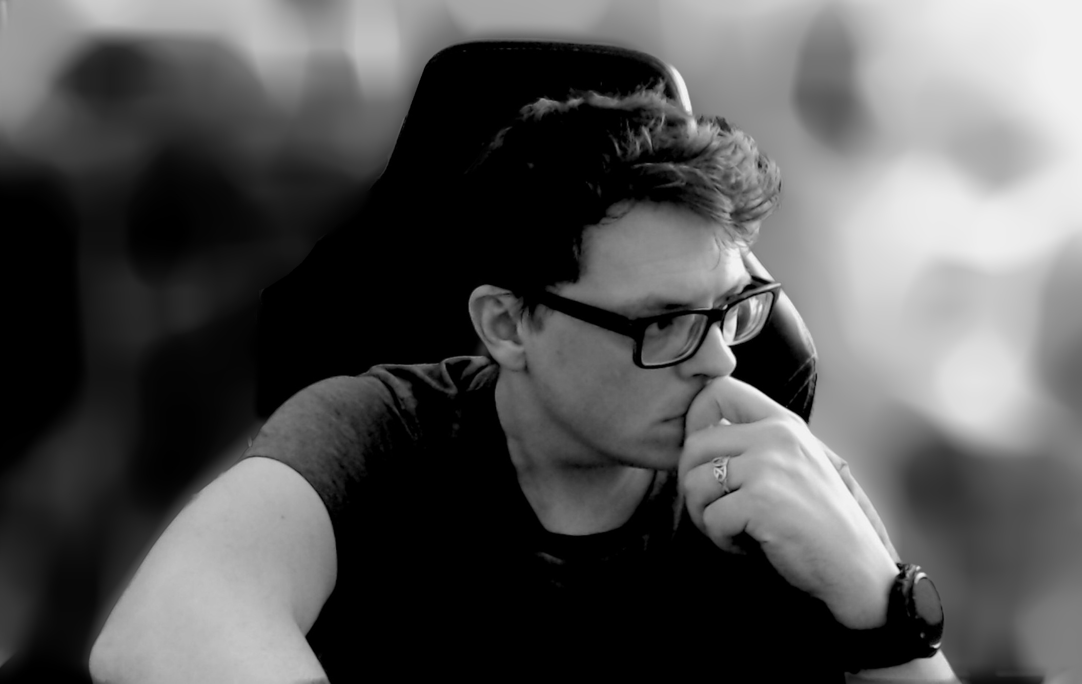 a black and white photo of a man in glasses sitting in a chair