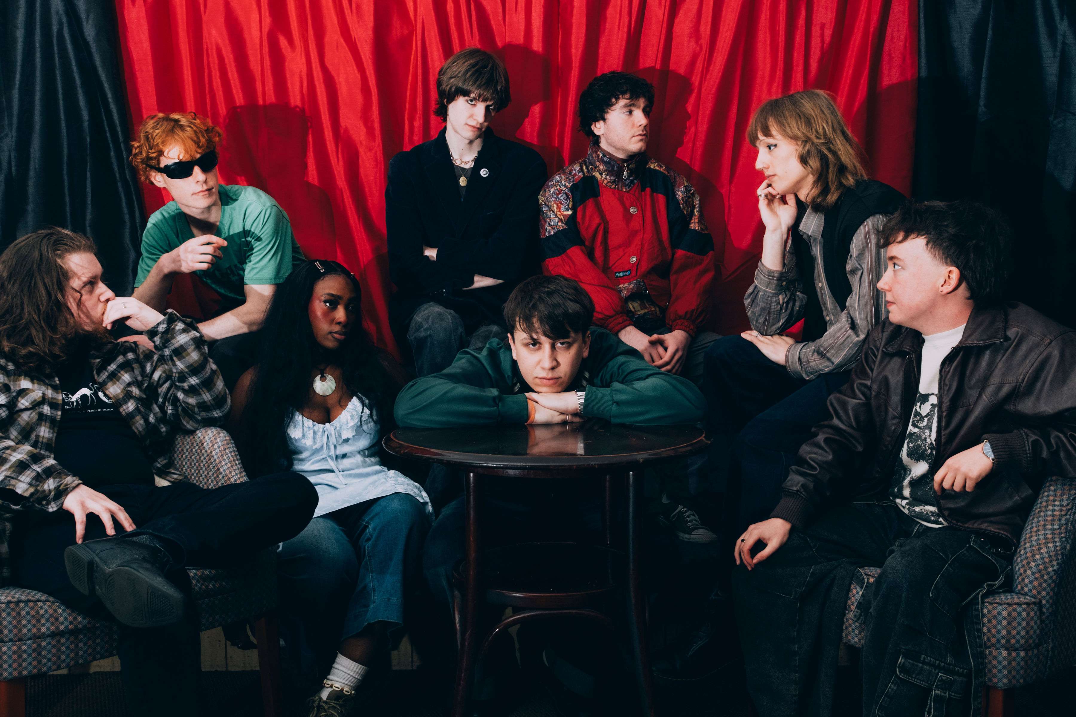 a group of people posing in front of a red curtain