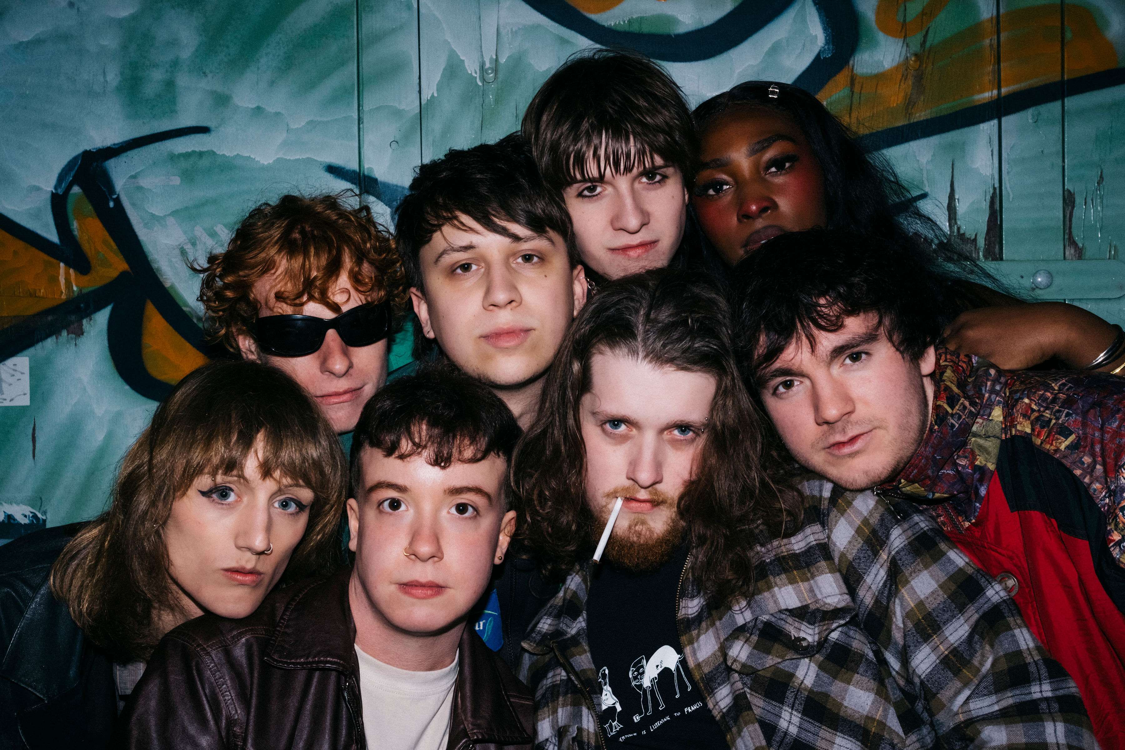 a group of young people posing in front of a graffiti wall