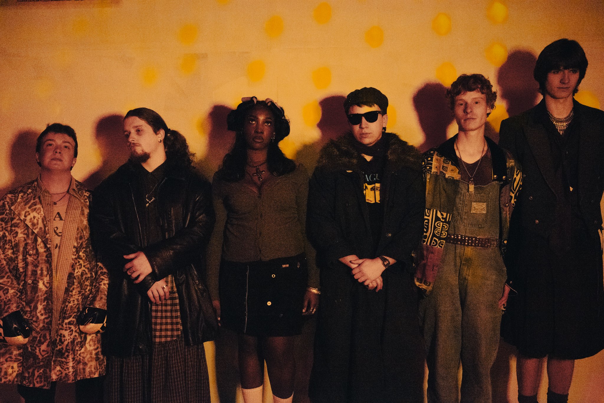 a group of people standing in front of a yellow wall