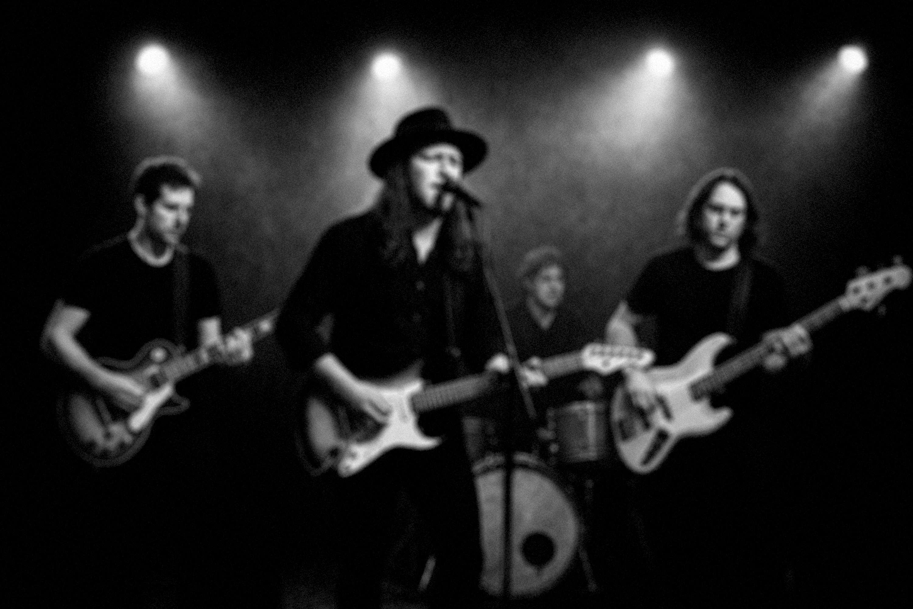 a black and white photo of a group of men playing guitars