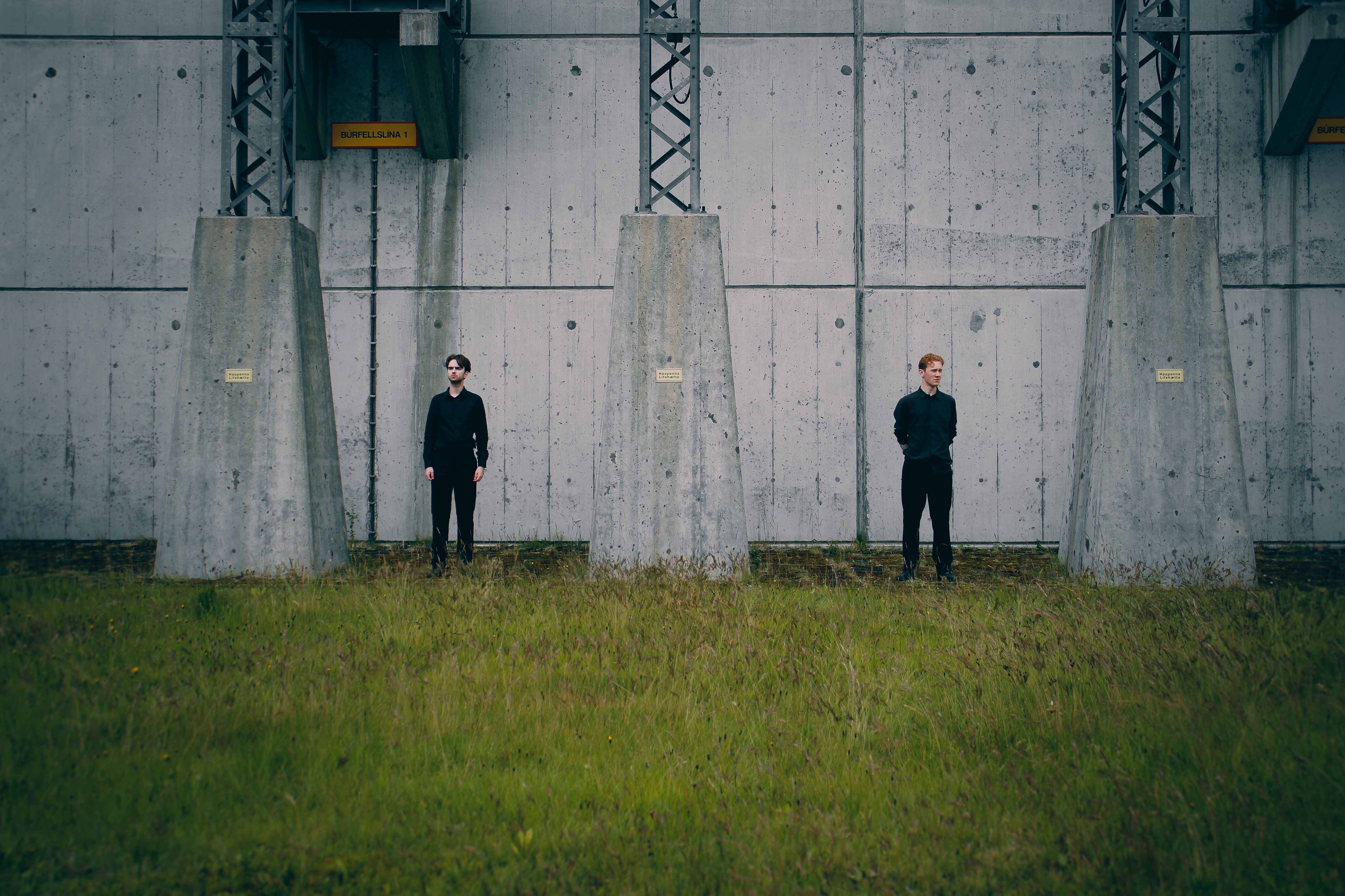 three men standing in front of a concrete wall