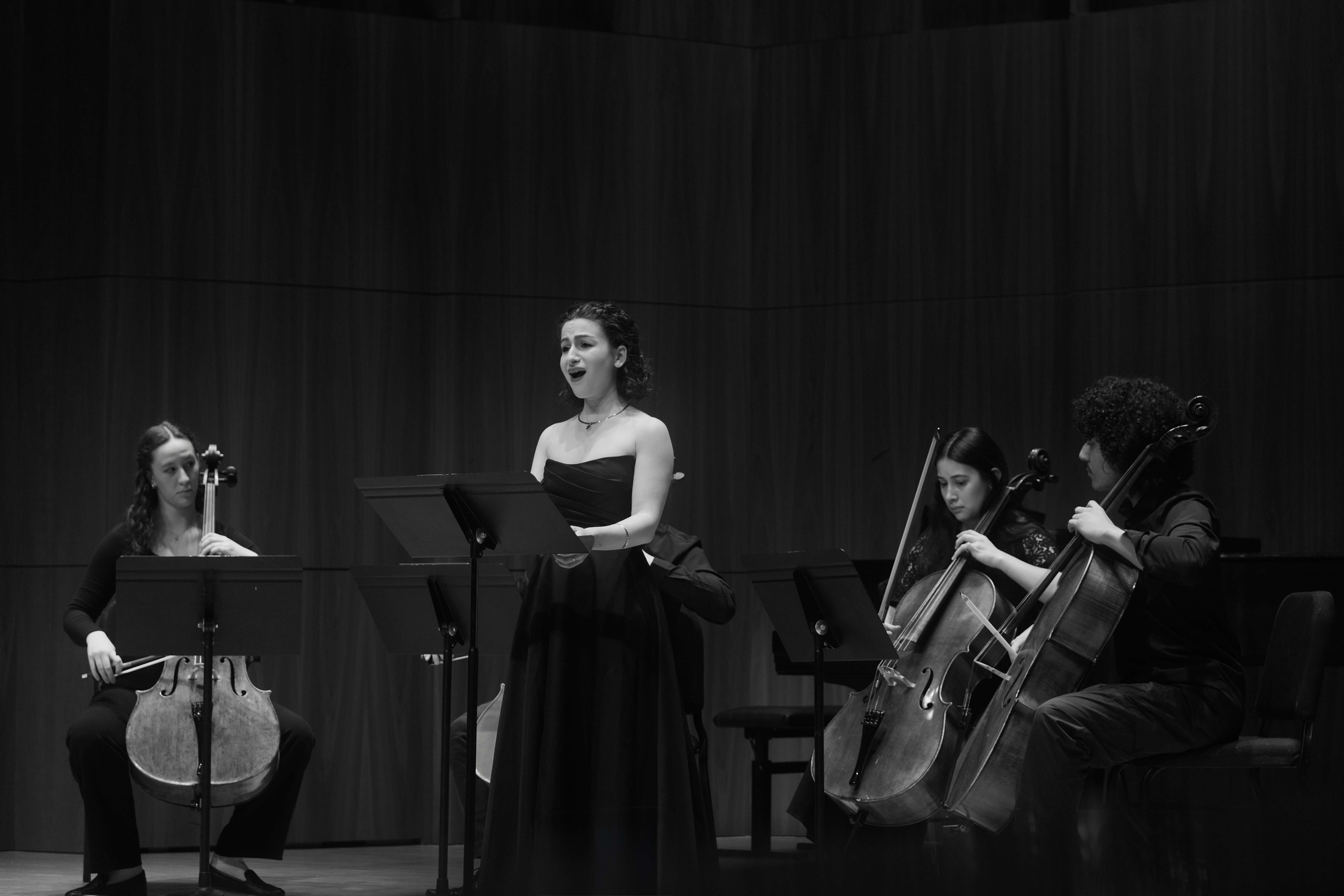 a black and white photo of a group of women playing cello