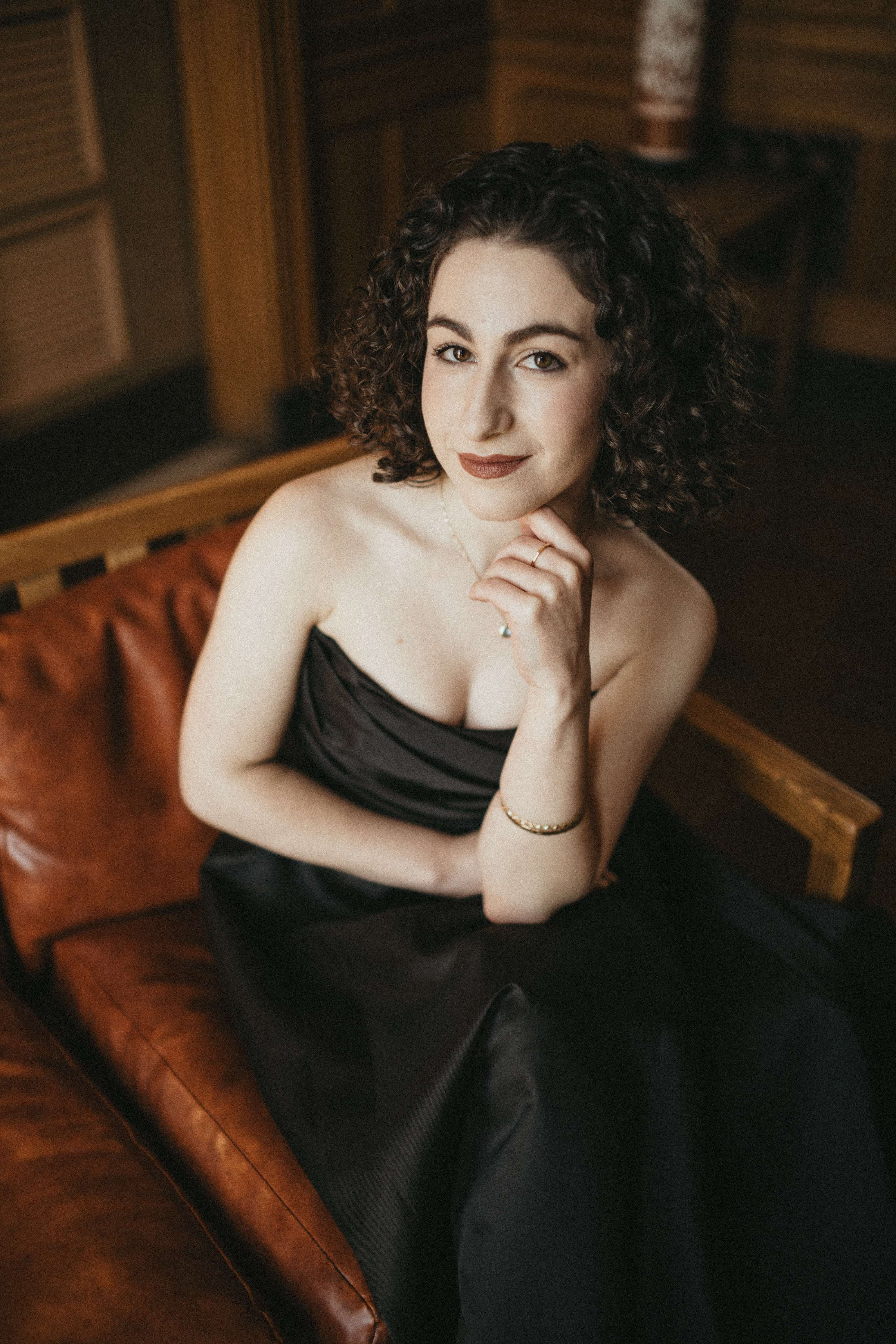 a woman in a black dress sitting on a leather couch