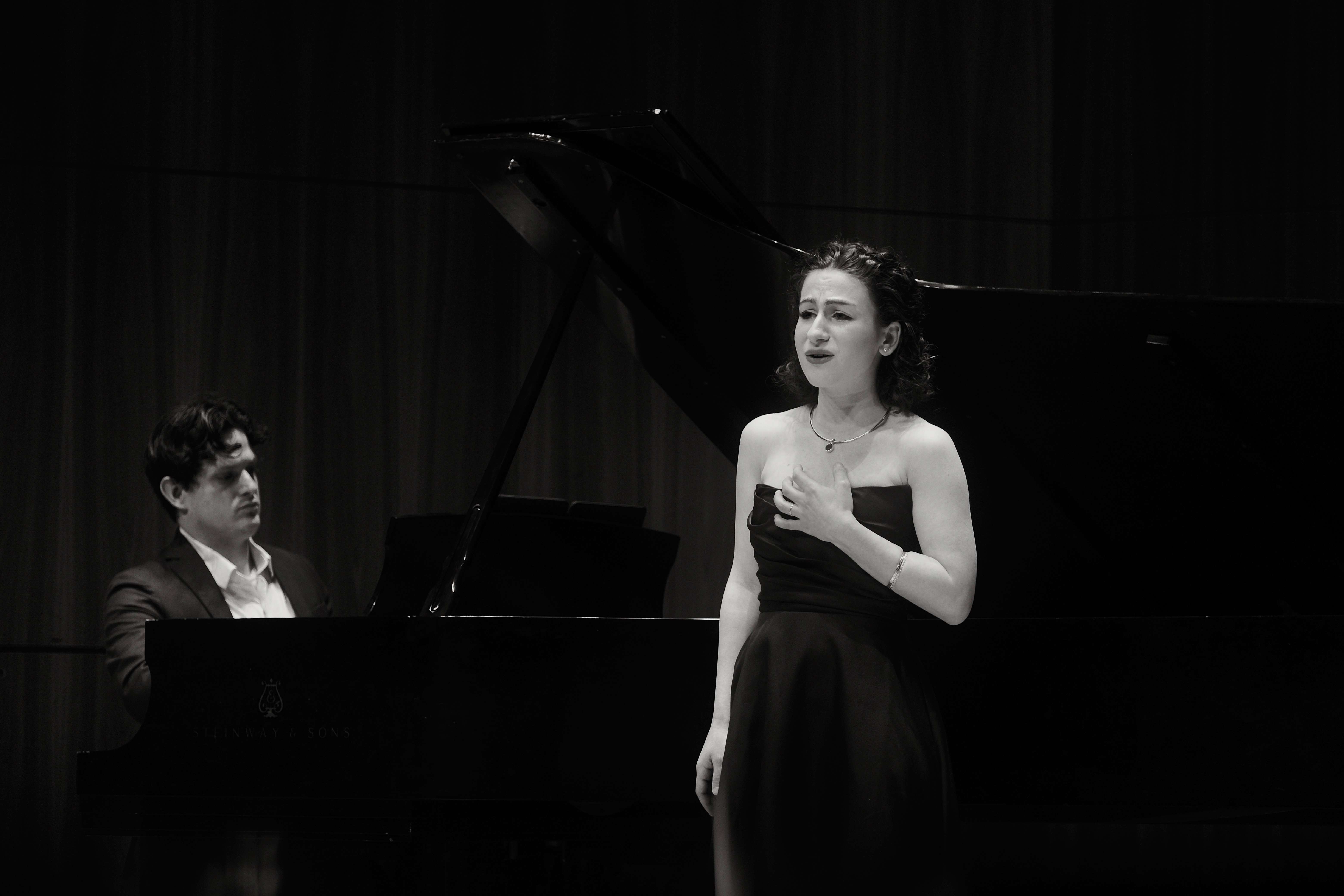 a man and woman standing next to a piano