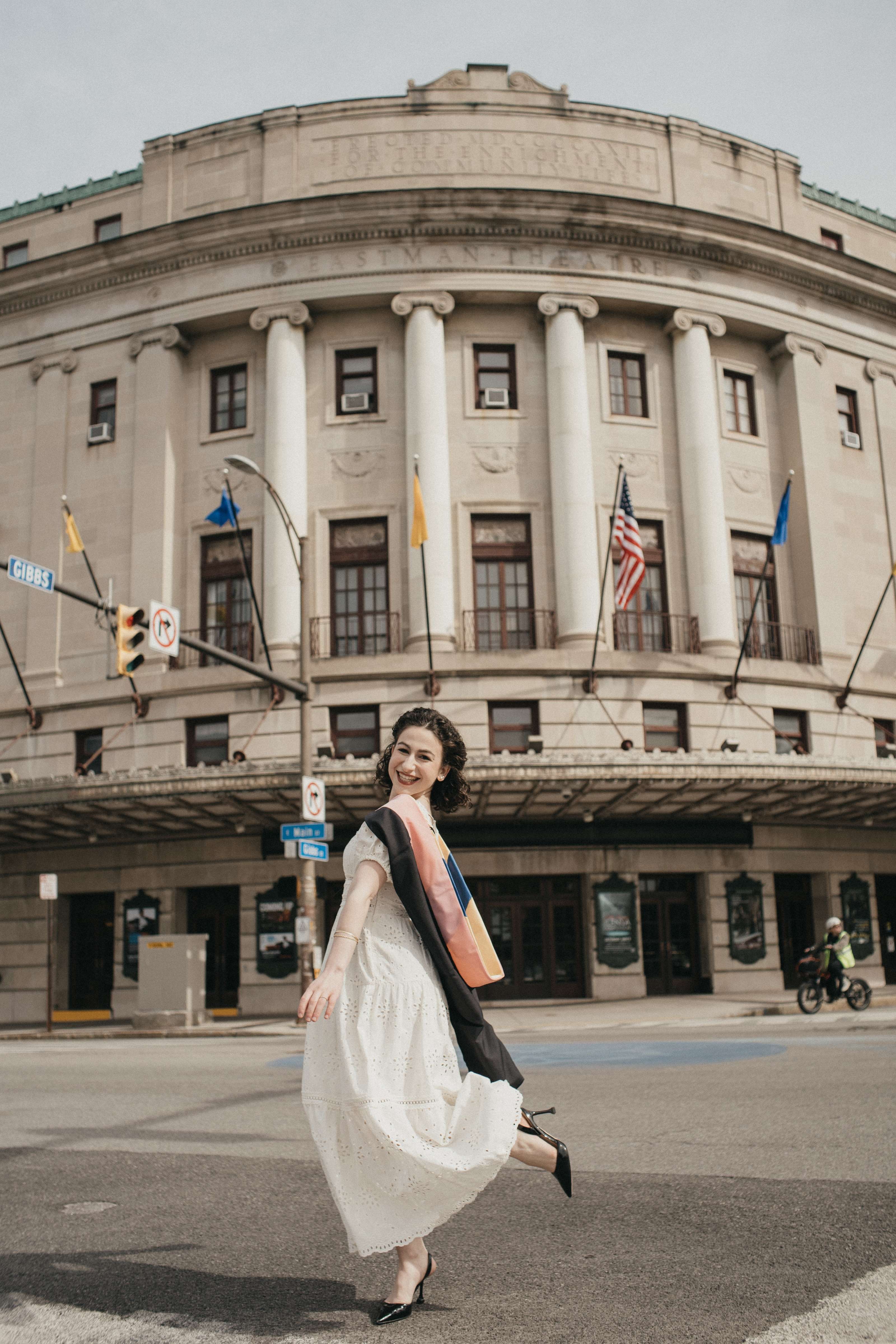 a woman in a white dress standing in front of a large building