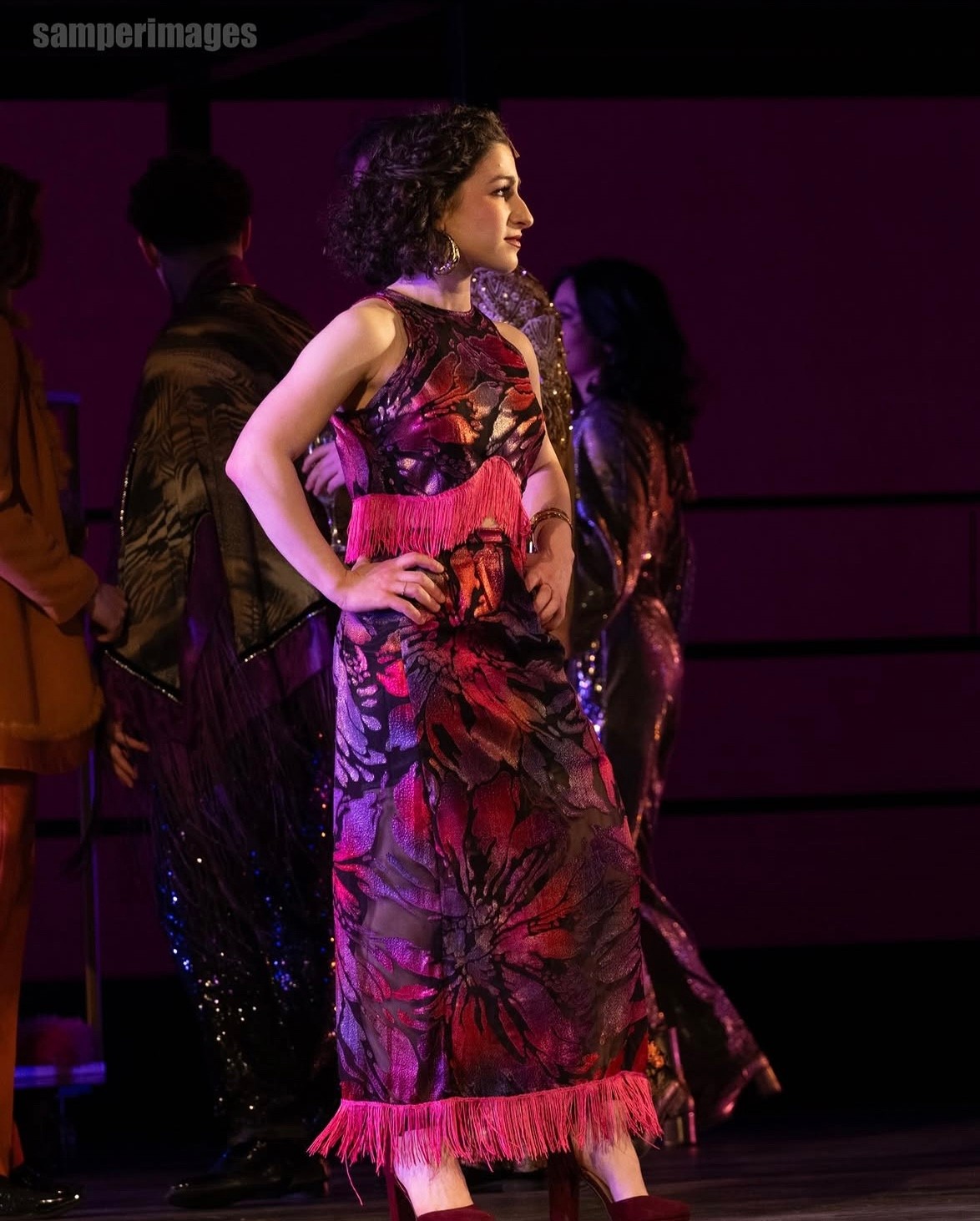 a woman in a dress on stage with other people
