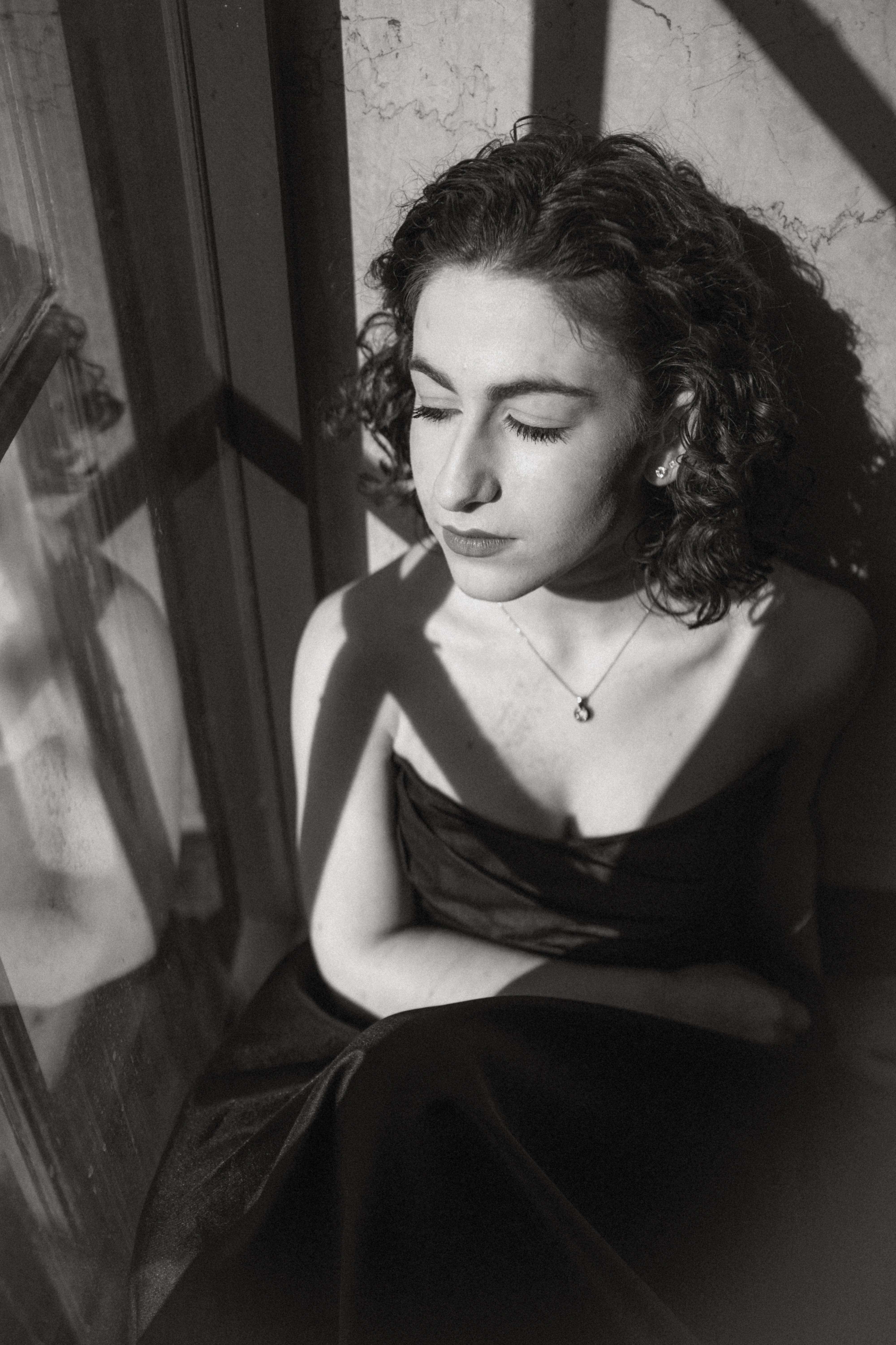 a black and white photo of a woman sitting in a window
