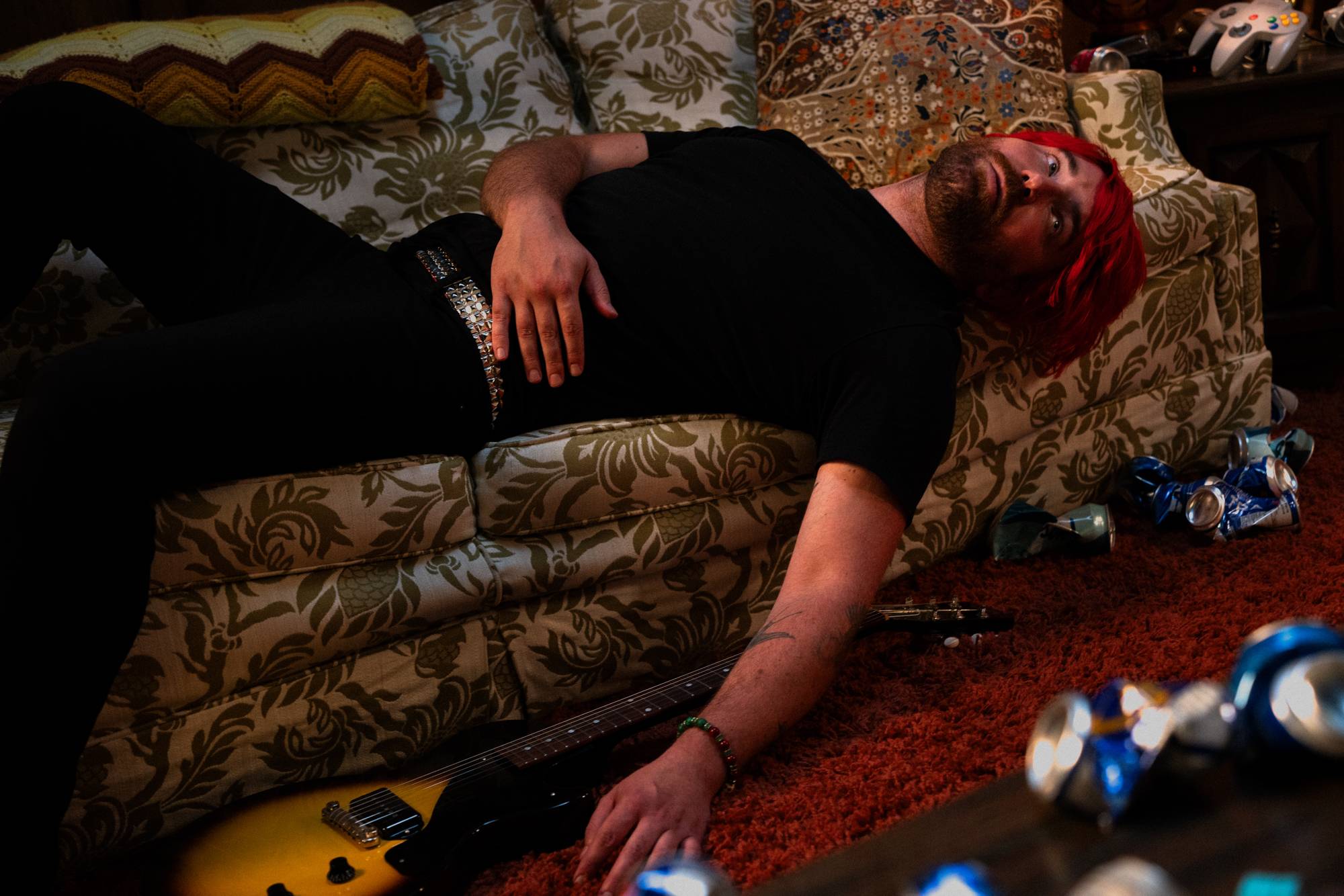 a man laying on a couch with beer cans on the floor