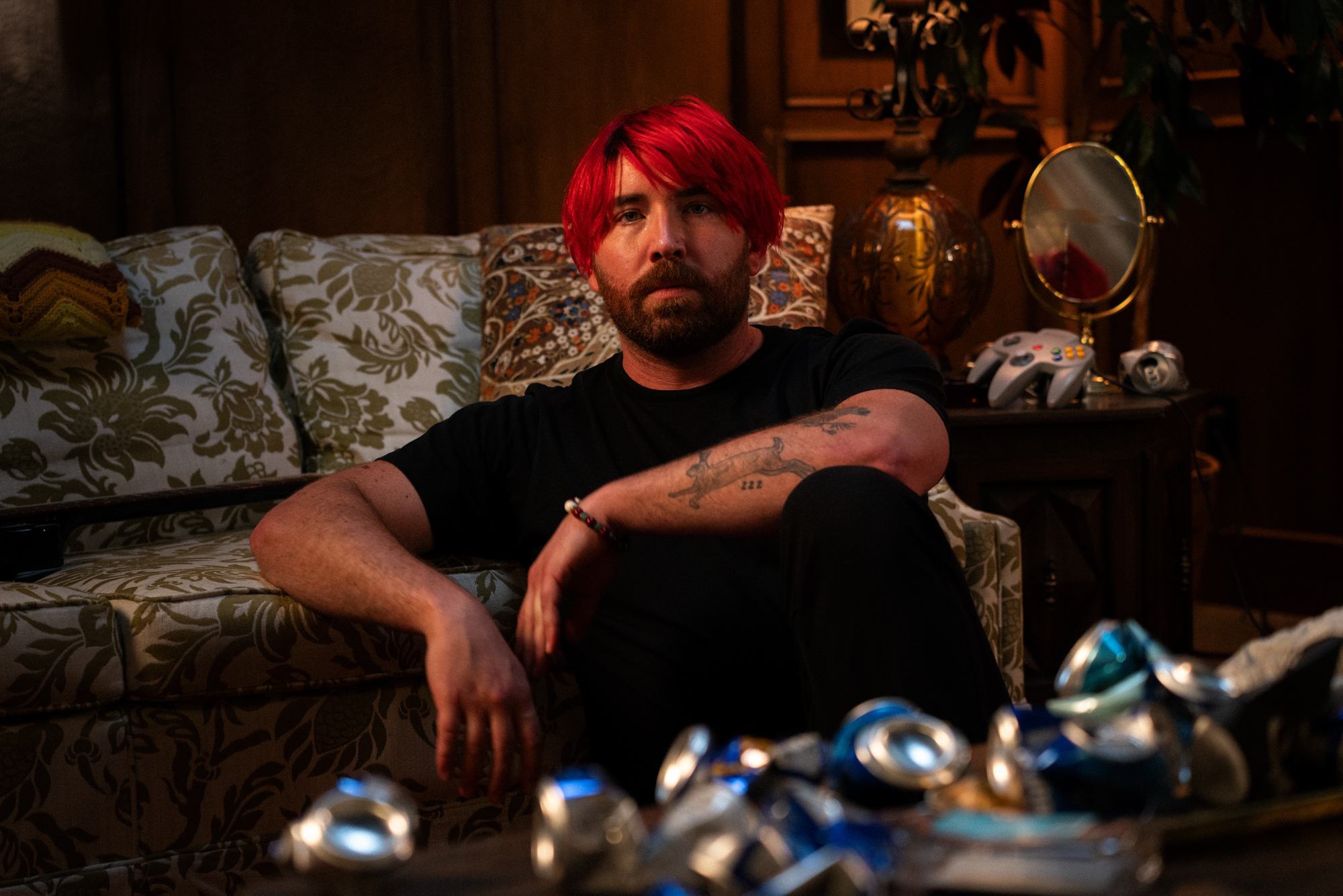 a man with red hair sitting on a couch with cans
