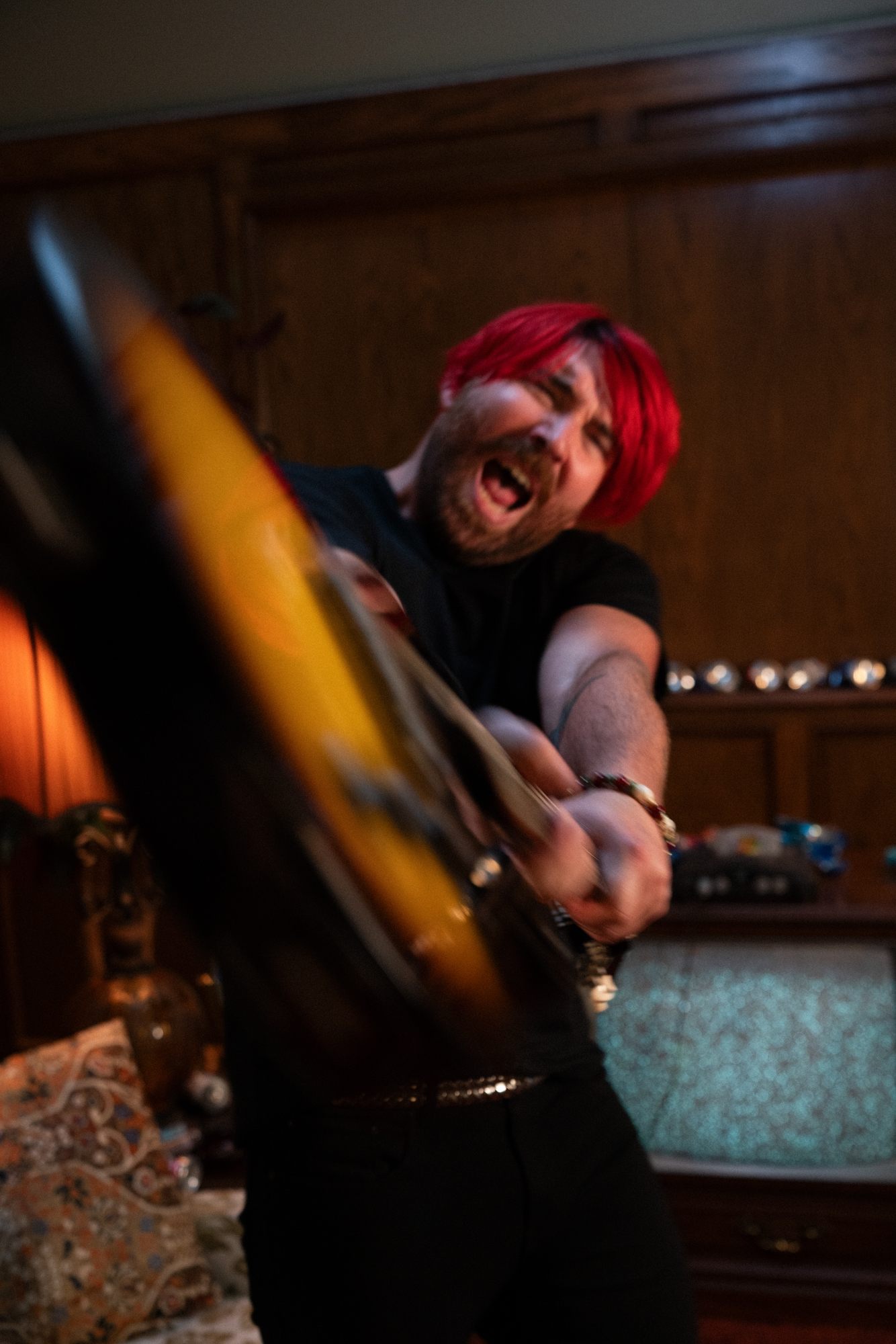 a man with red hair playing a guitar in a living room