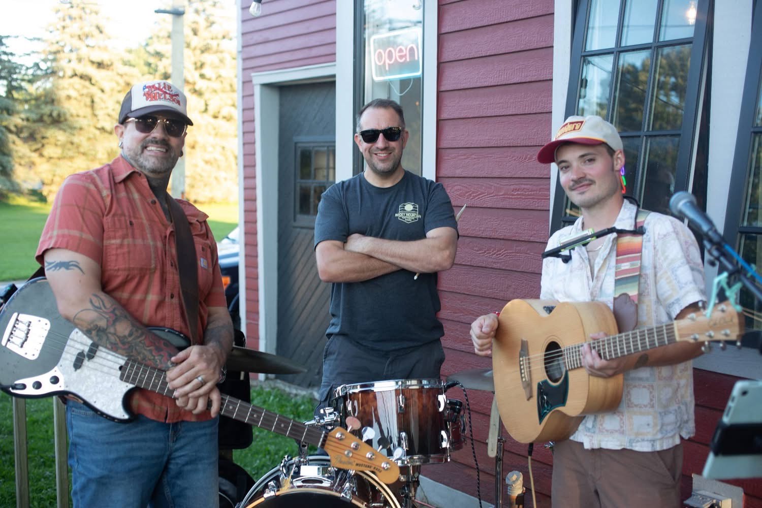 three men standing in front of a building with guitars