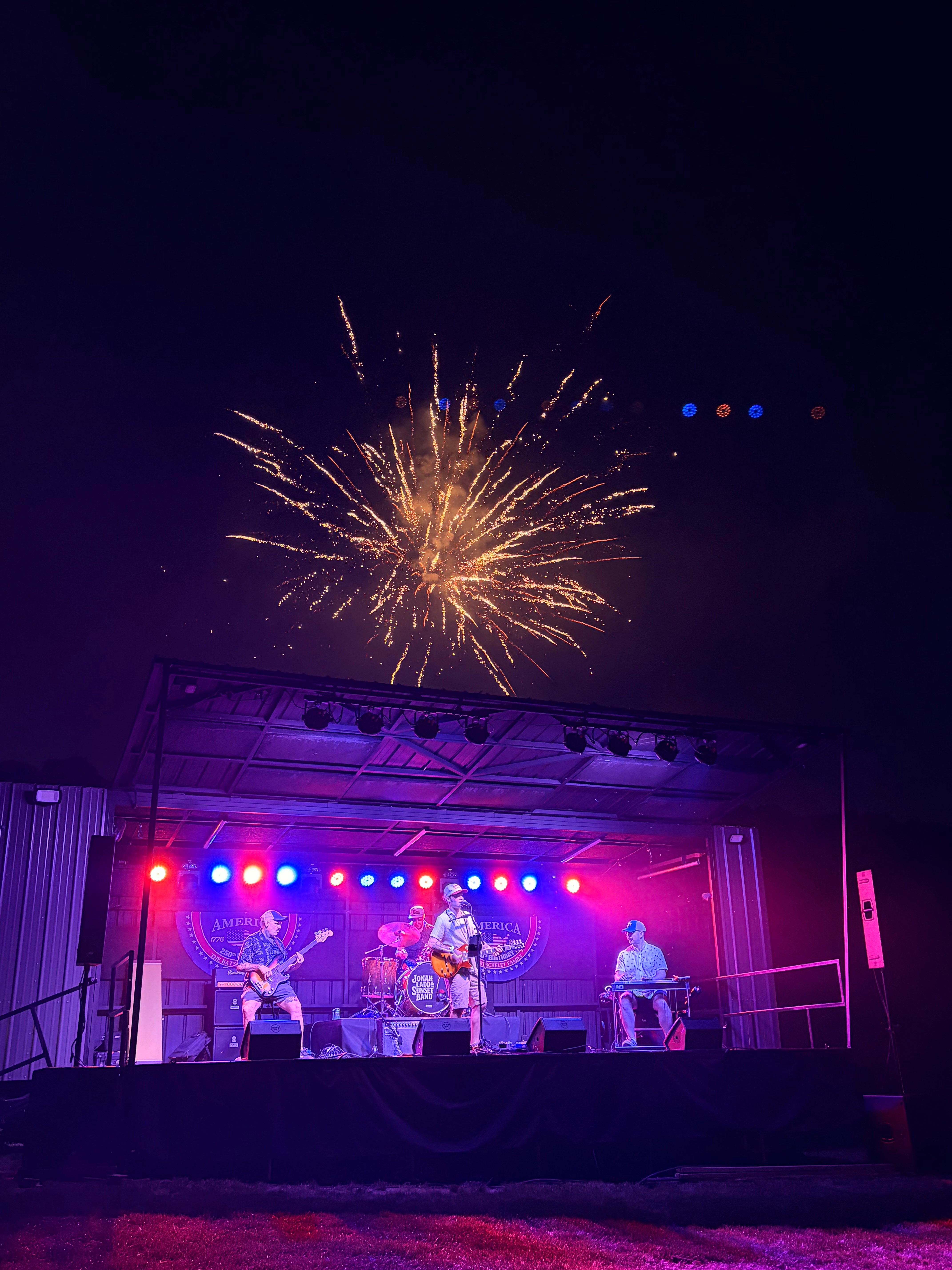 a group of people on a stage with a firework in the sky