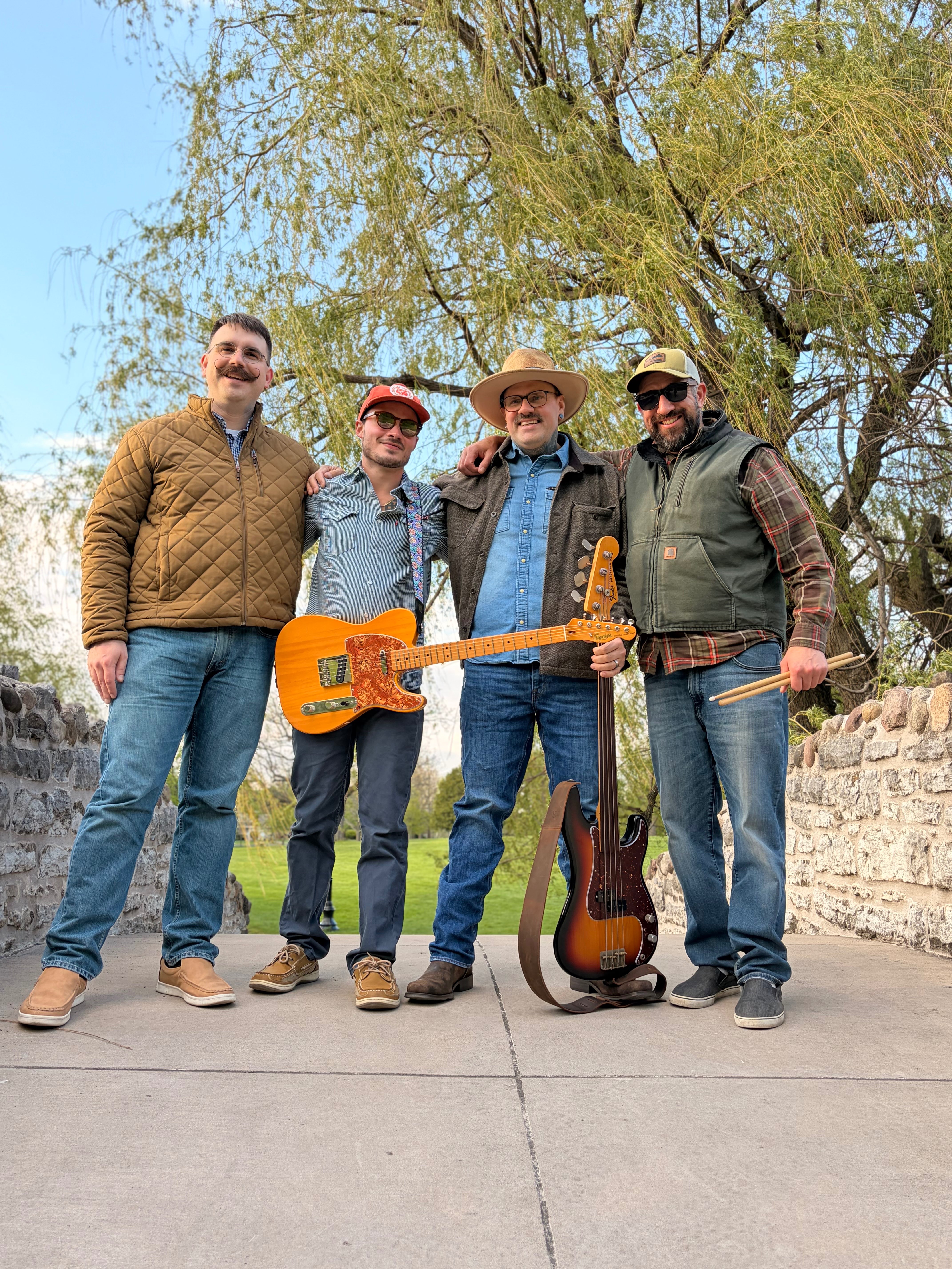 four men posing for a picture with a guitar