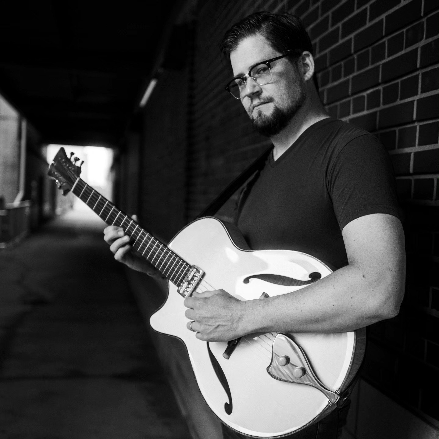 a black and white photo of a man holding a guitar