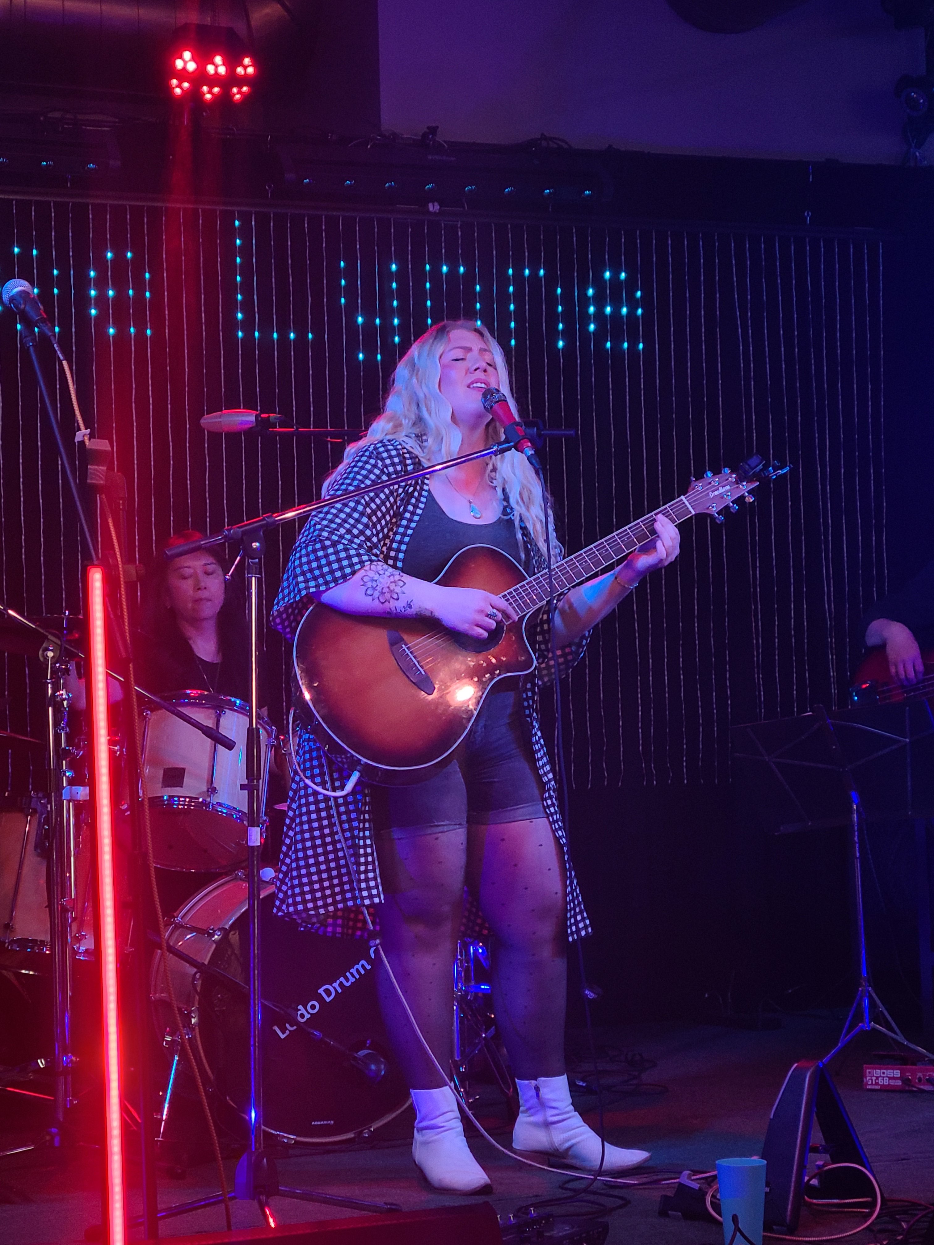 a woman singing and playing an acoustic guitar on stage