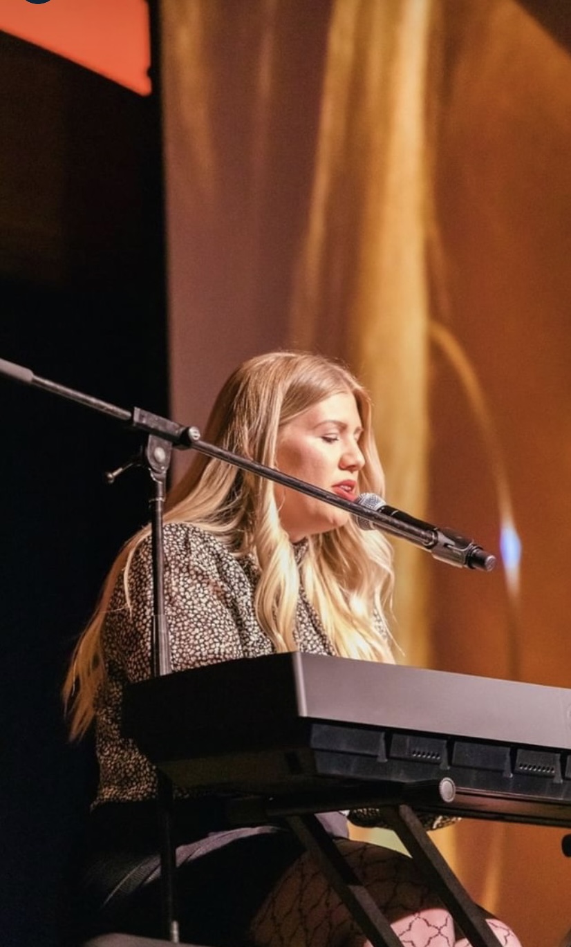 a woman sitting at a keyboard in front of a microphone