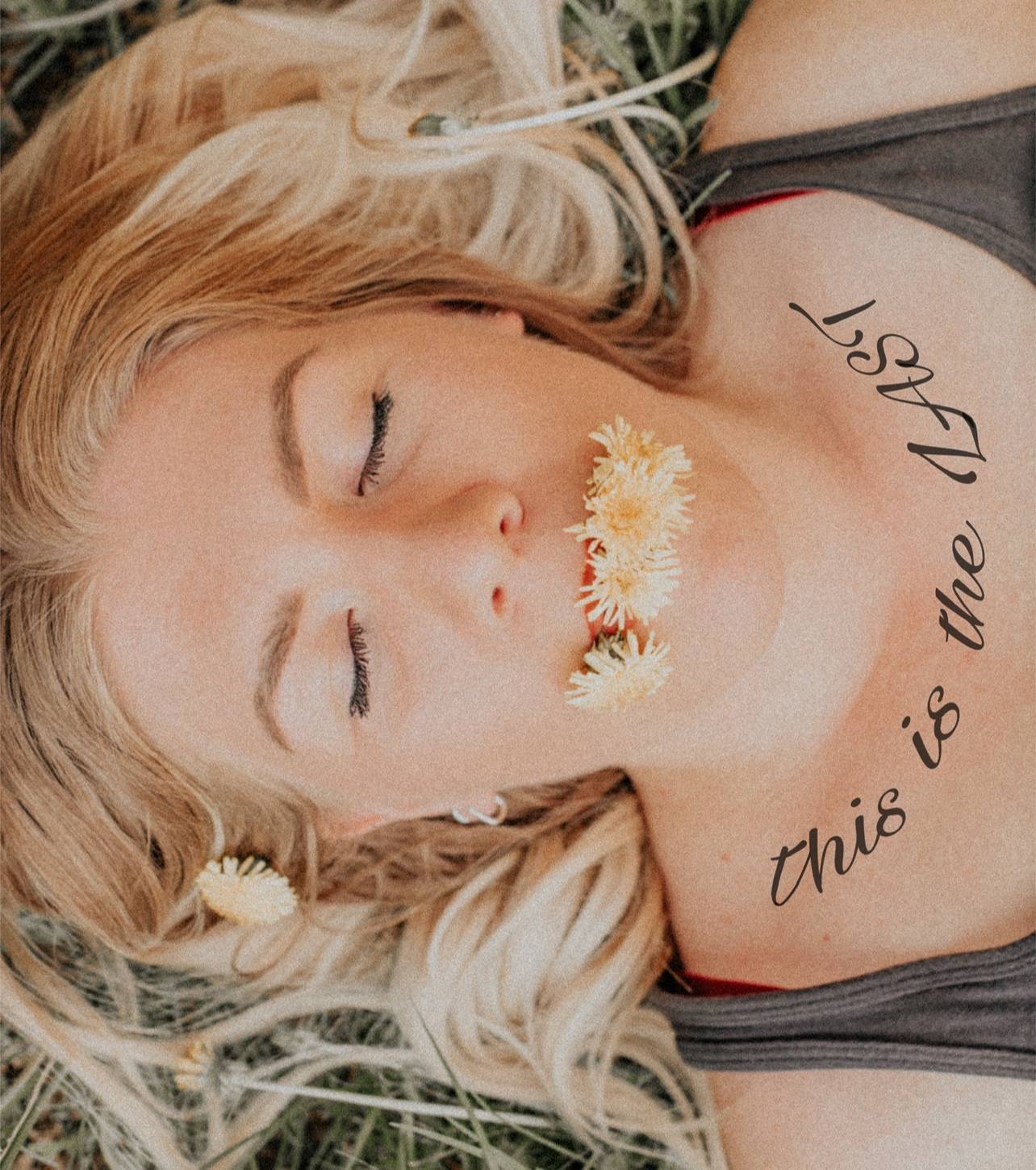 a woman laying in the grass with a flower in her mouth