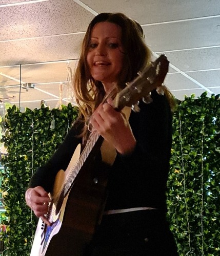 a woman playing an acoustic guitar in a restaurant