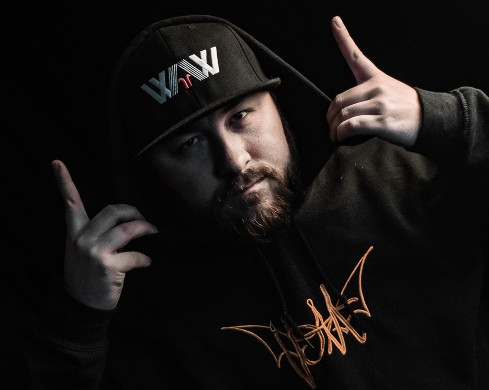 a bearded man in a black hoodie pointing his fingers