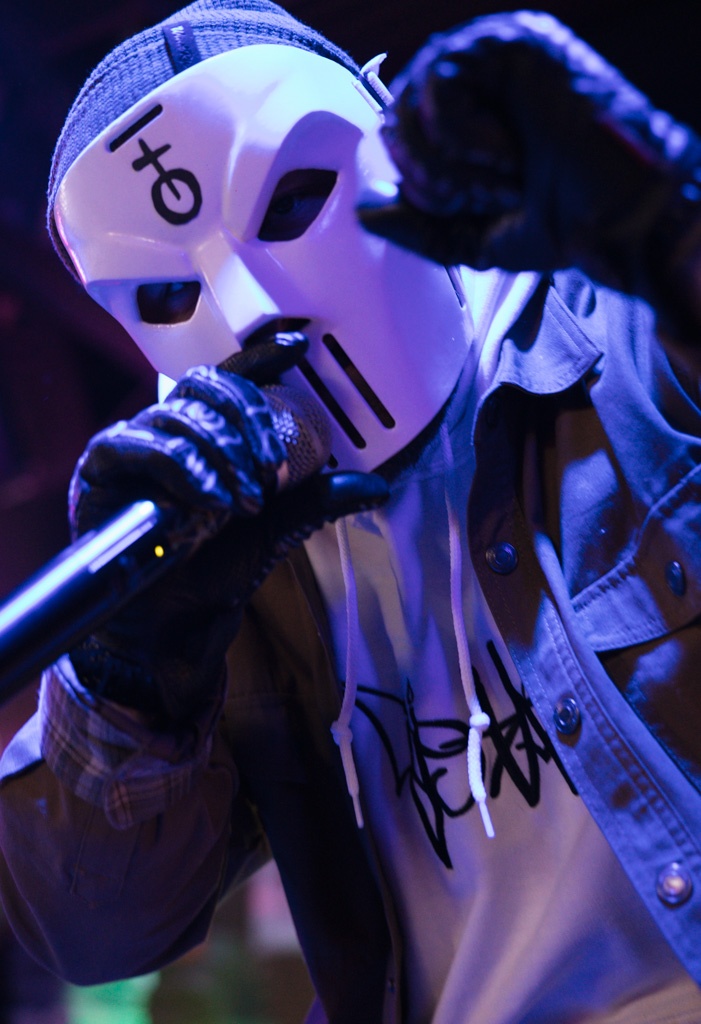 a man in a white mask holding a microphone