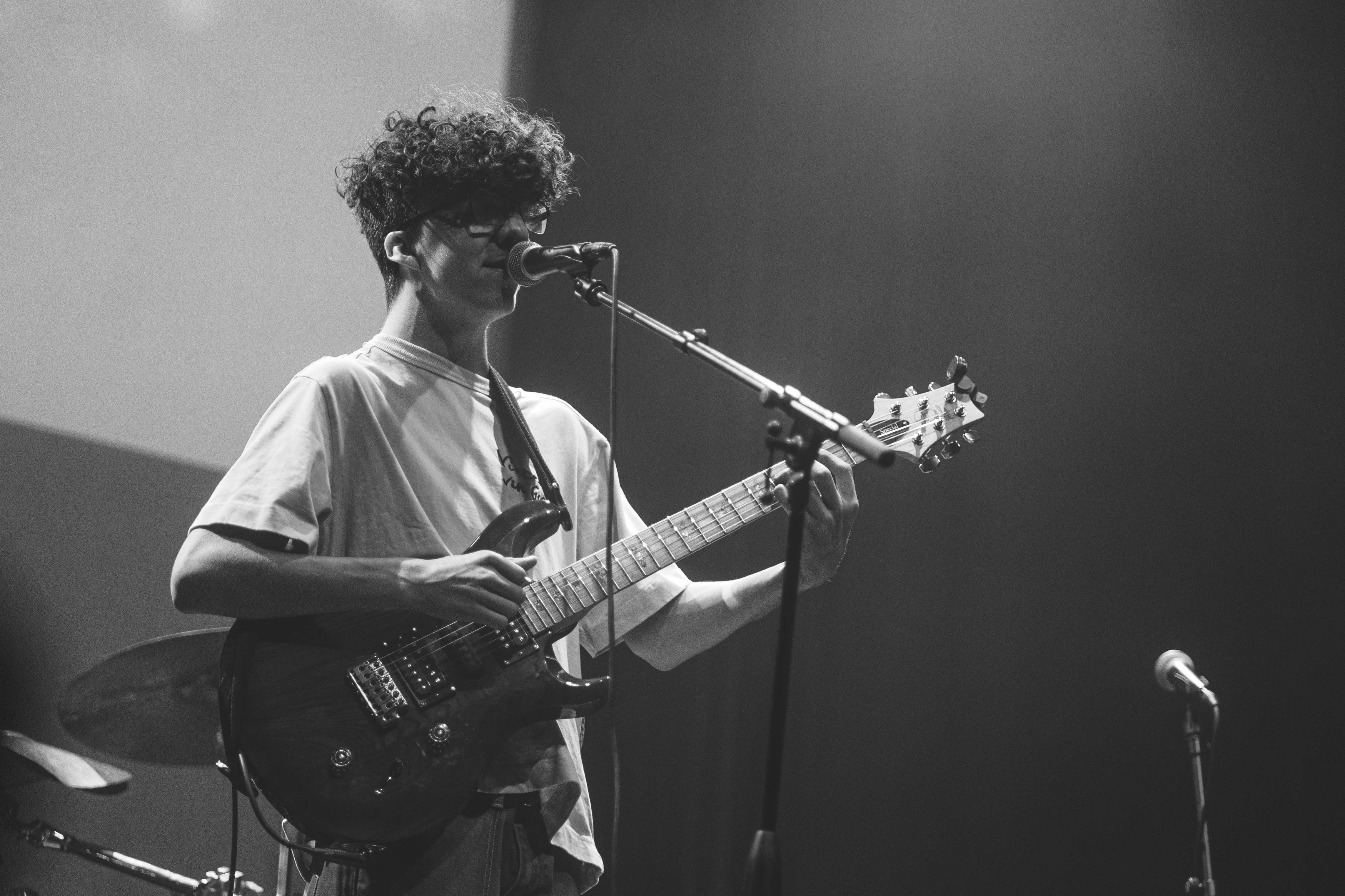 a young man playing a guitar in front of a microphone