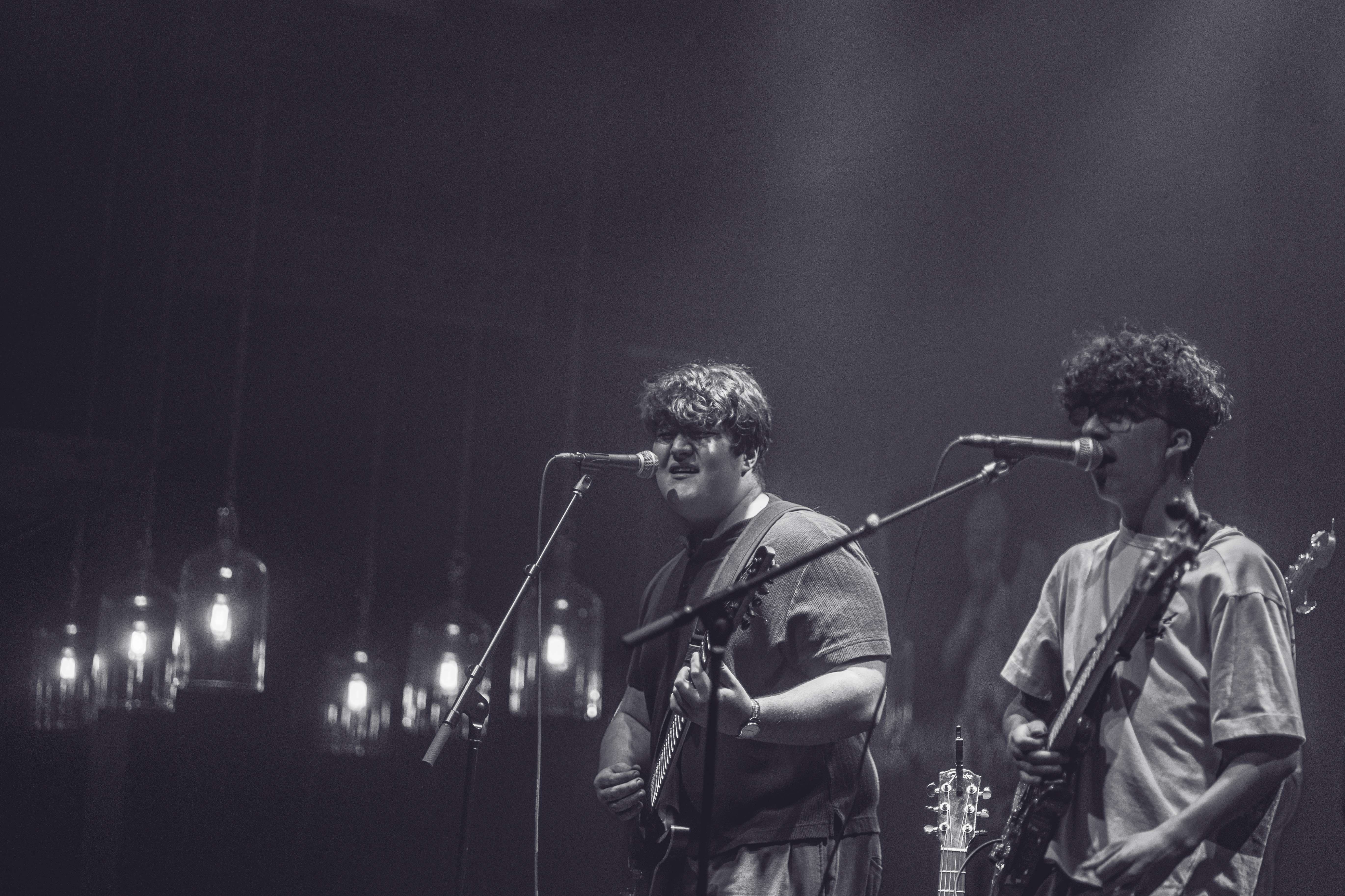 two men on stage with guitars and microphones