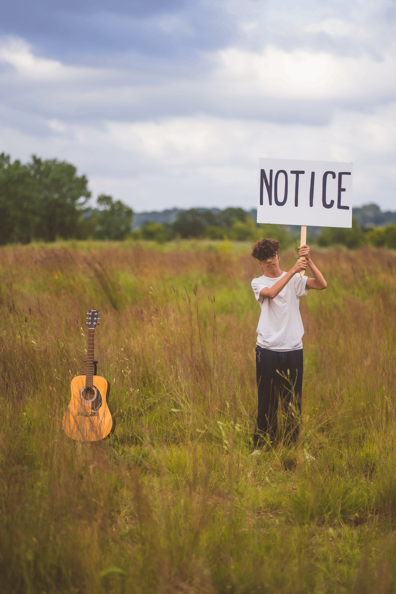 a person standing in a field holding a sign that says not ice