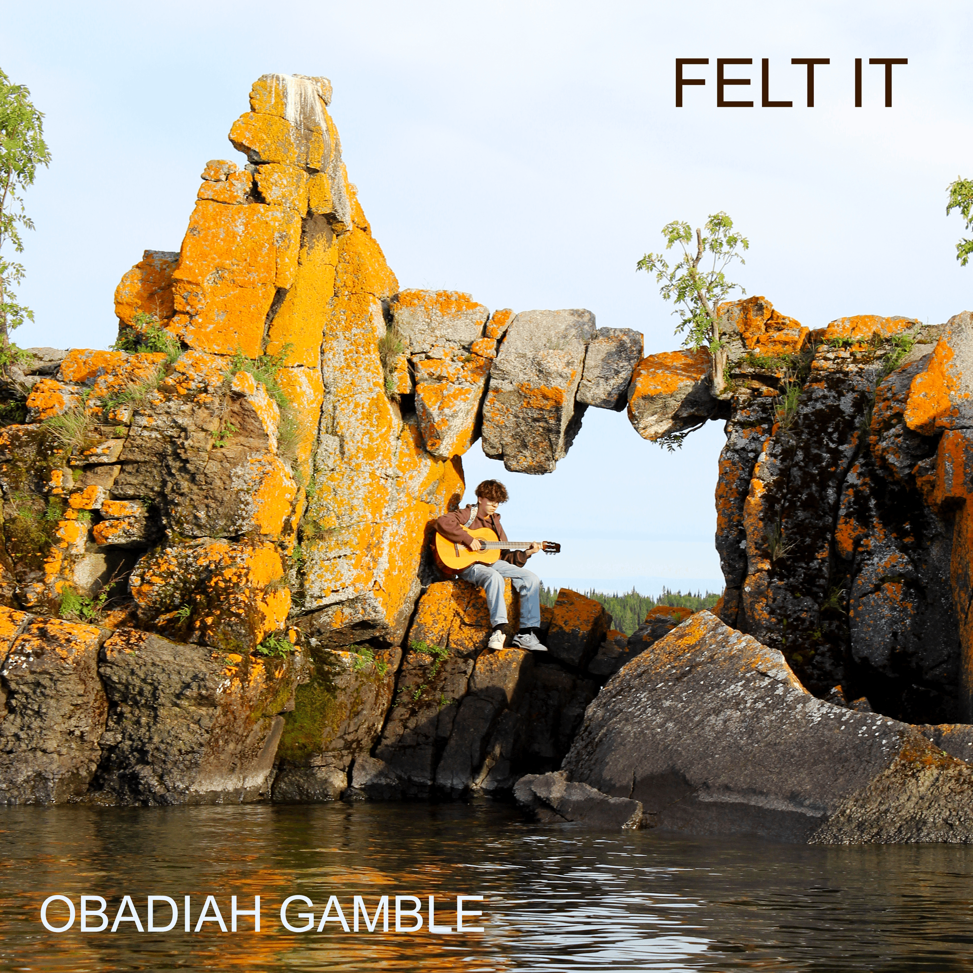 Obadiah Gamble - Felt It: a man playing an acoustic guitar on a rock