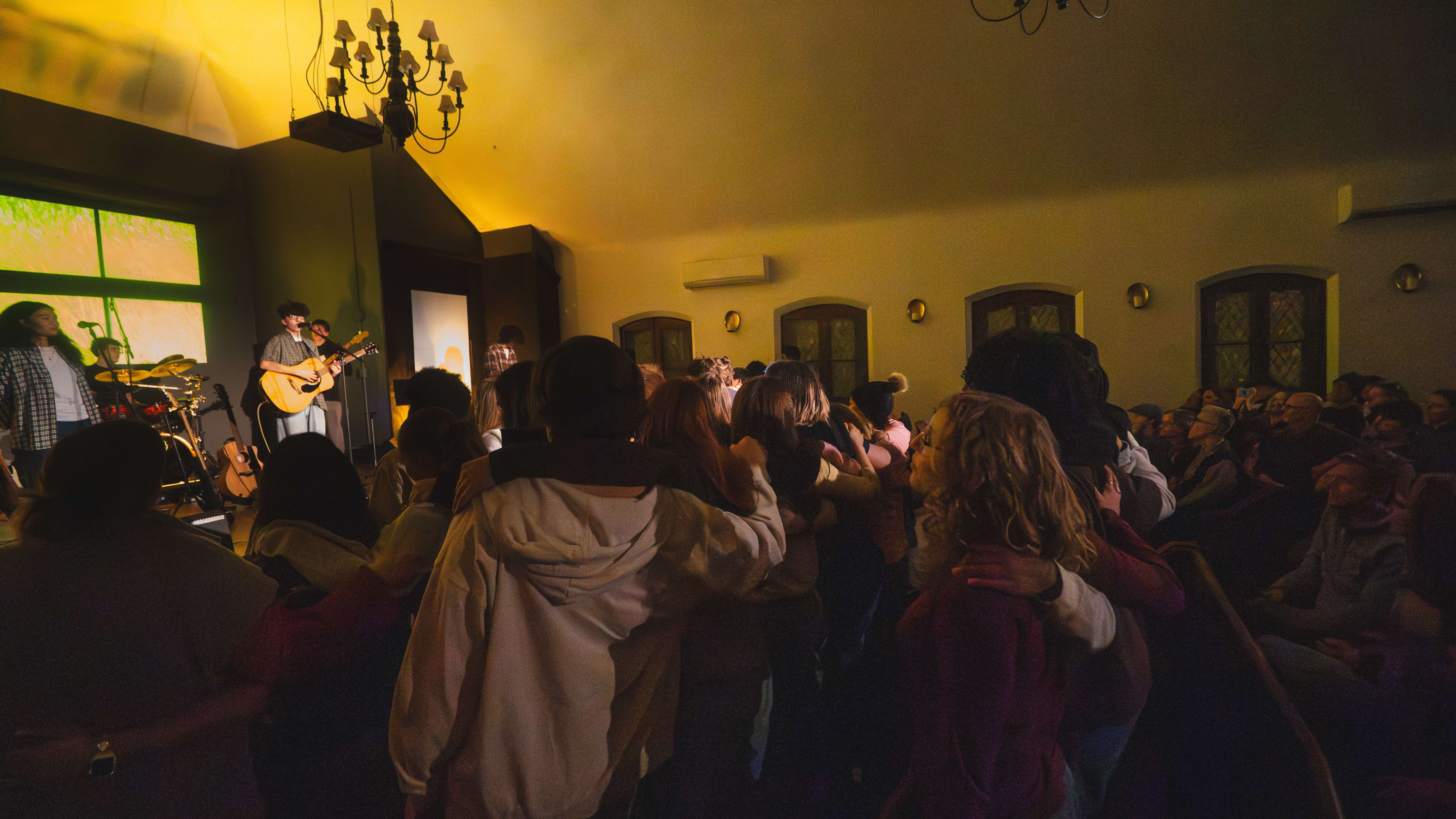 a group of people standing in a church with an acoustic guitar