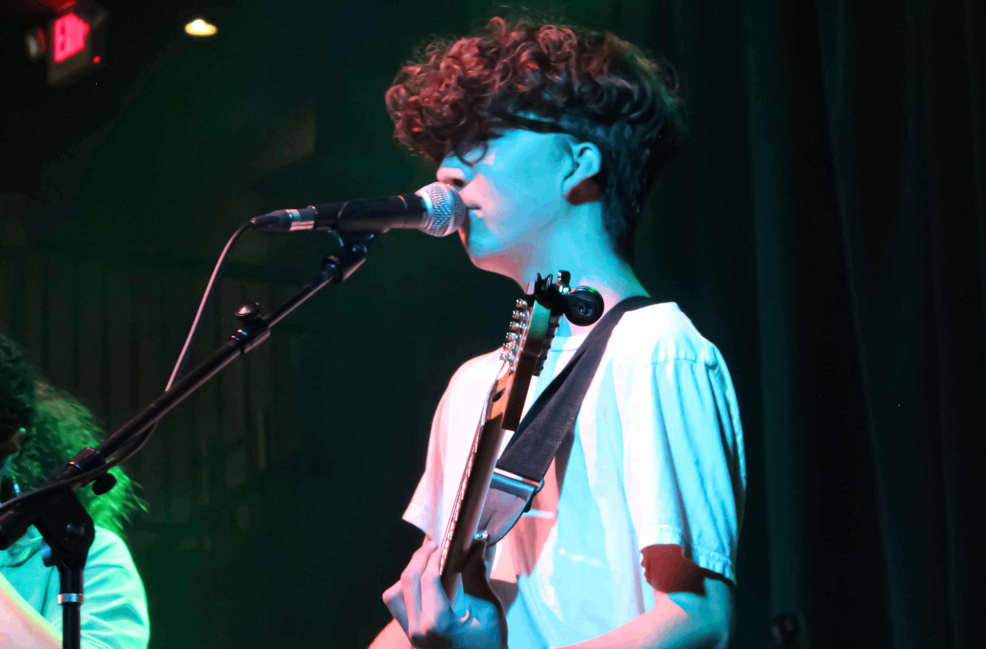 a young man playing guitar on stage with a microphone