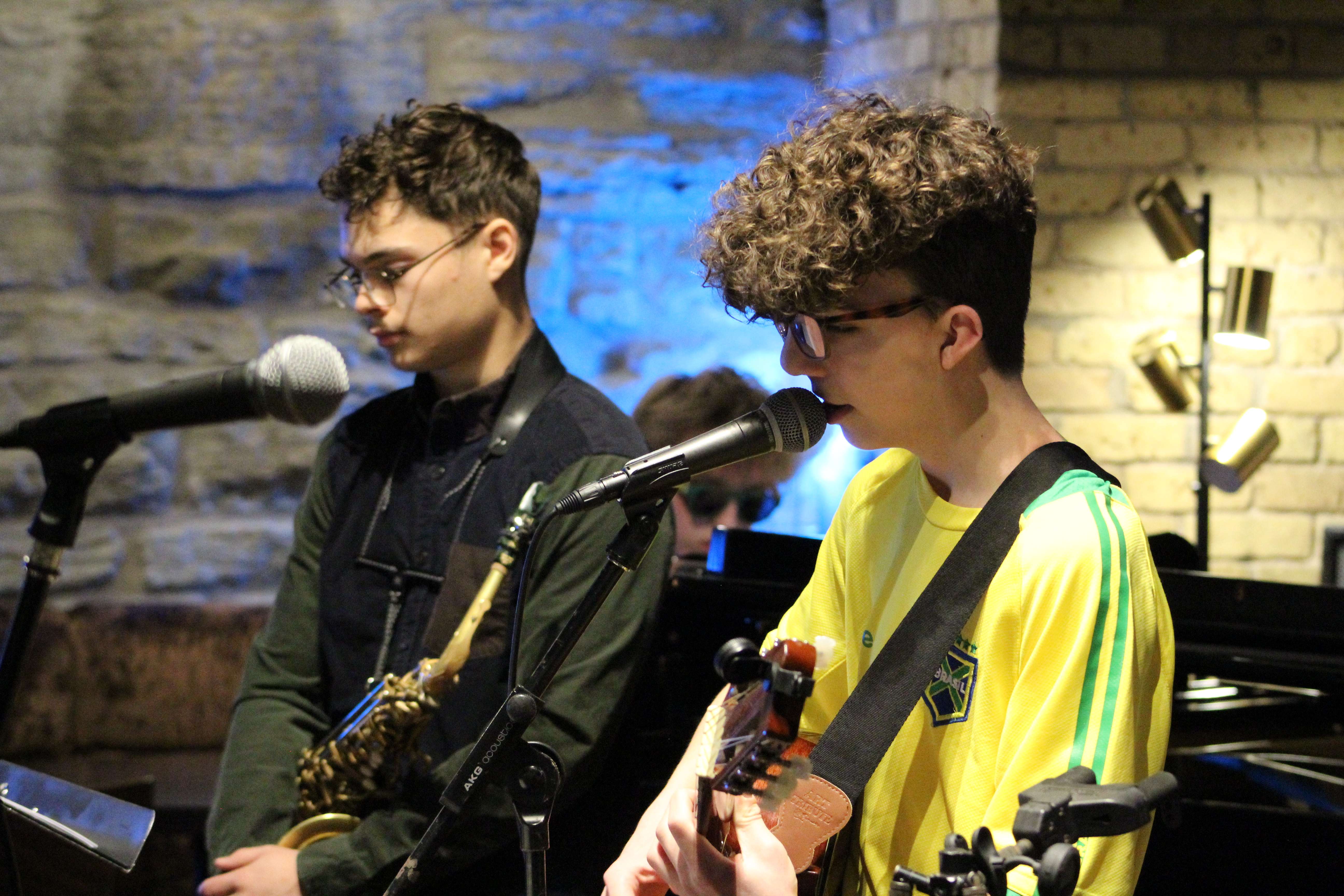 two young men playing instruments in front of a microphone