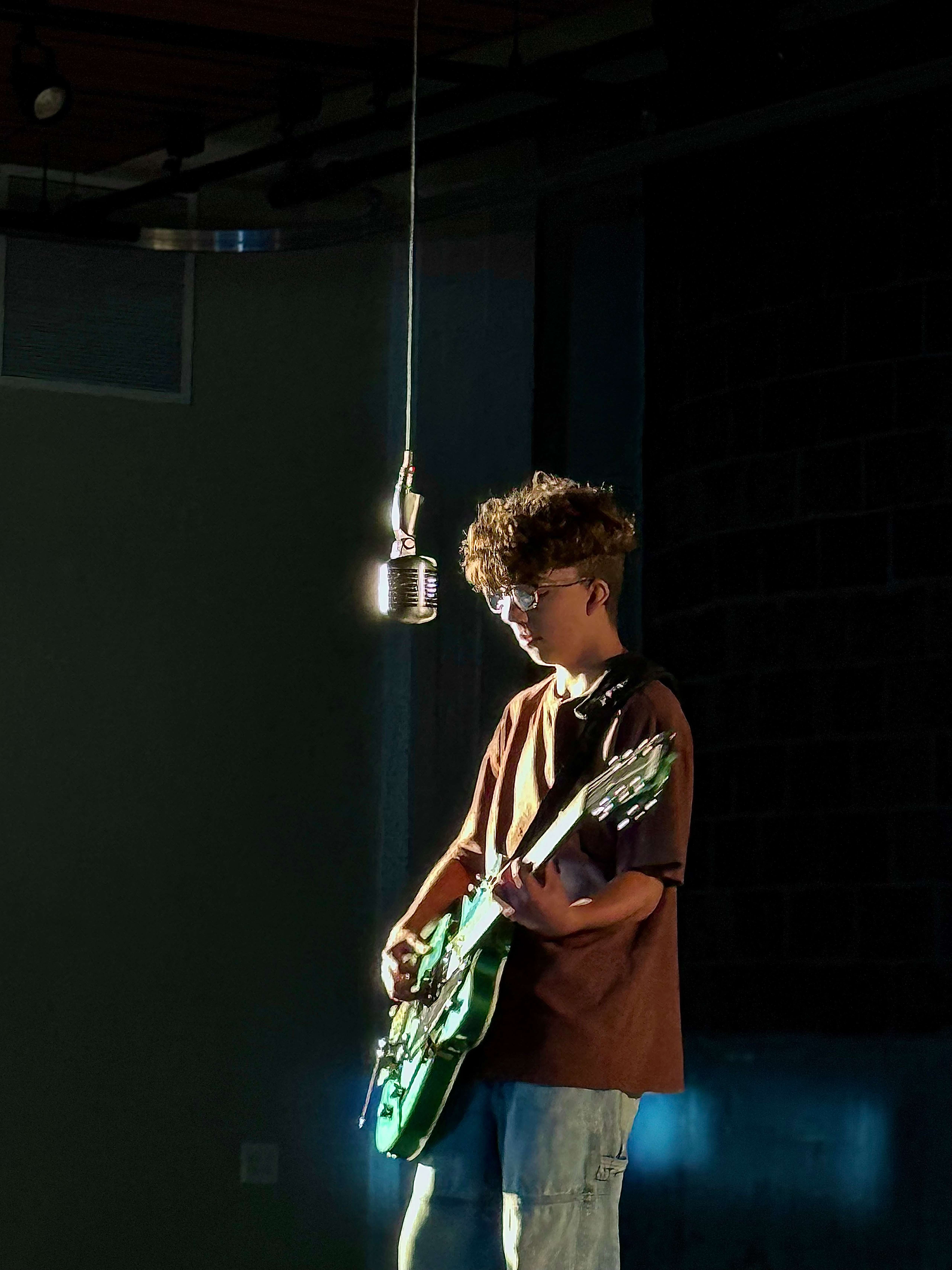 a young man playing a guitar in a dark room
