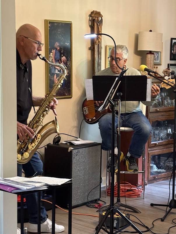three men playing saxophones in a living room
