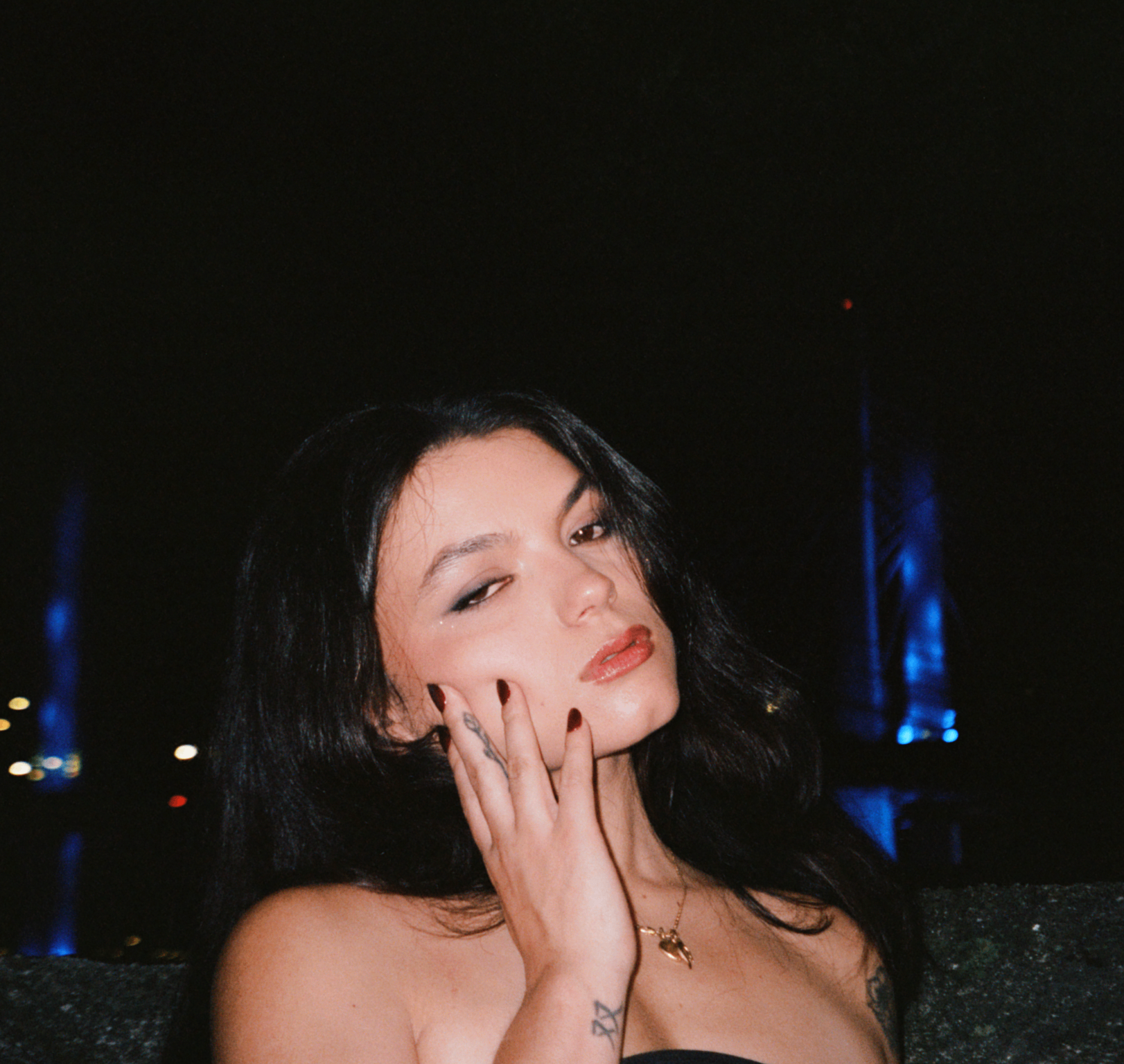 a woman in a black dress sitting on a bench at night