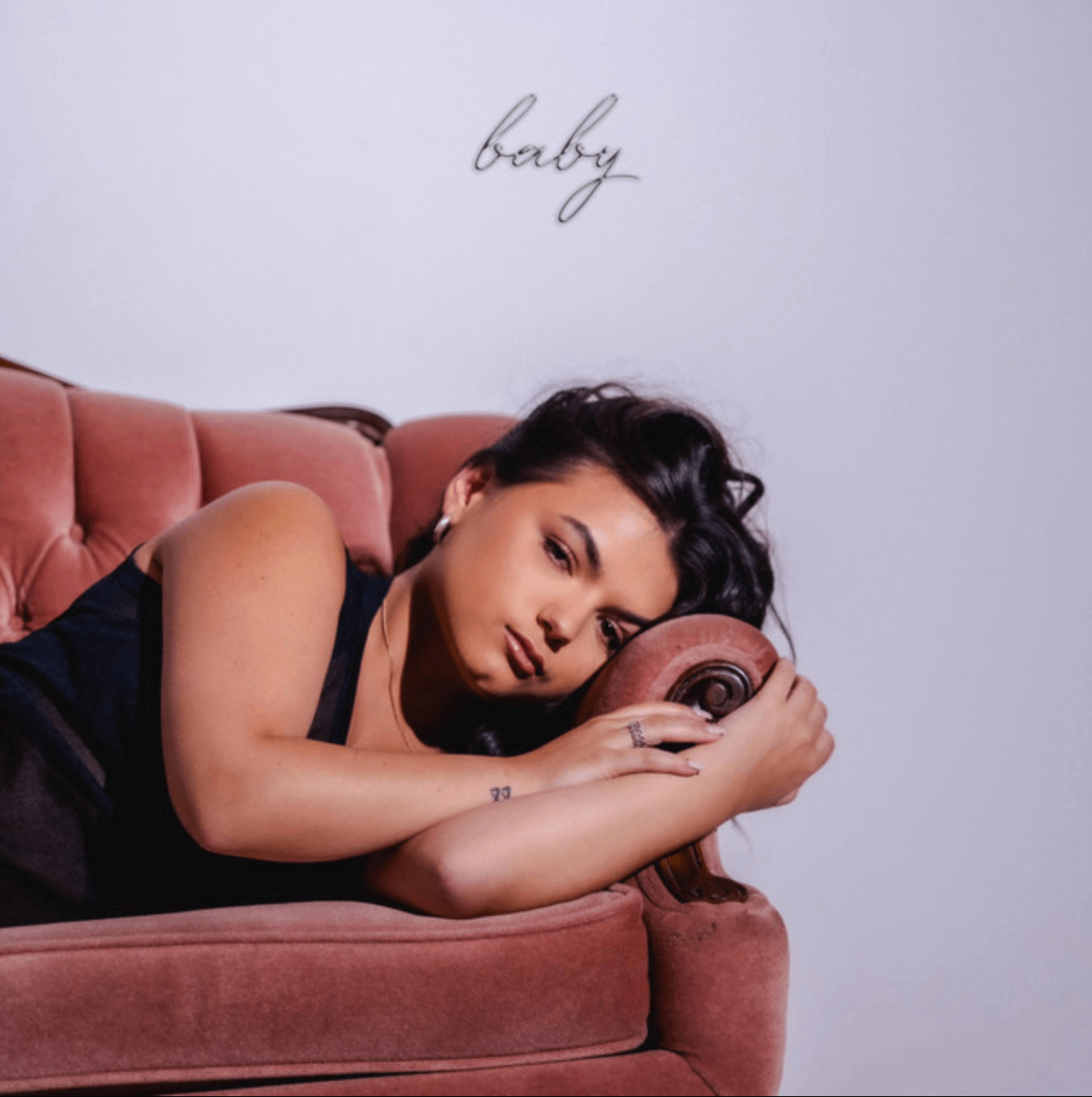 a woman laying on a pink chair with tattoos