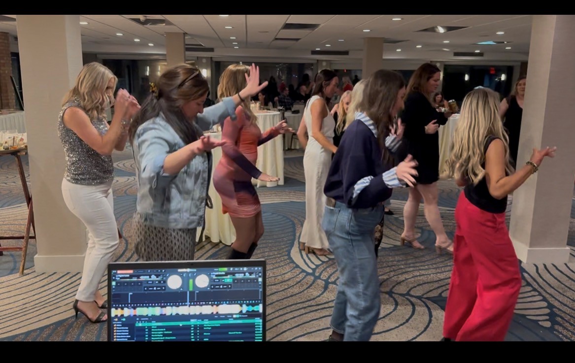 a group of people dancing in a room with a dj