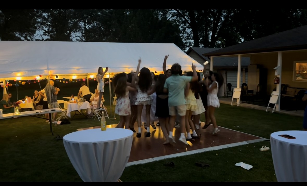 a group of people dancing at a party under a tent
