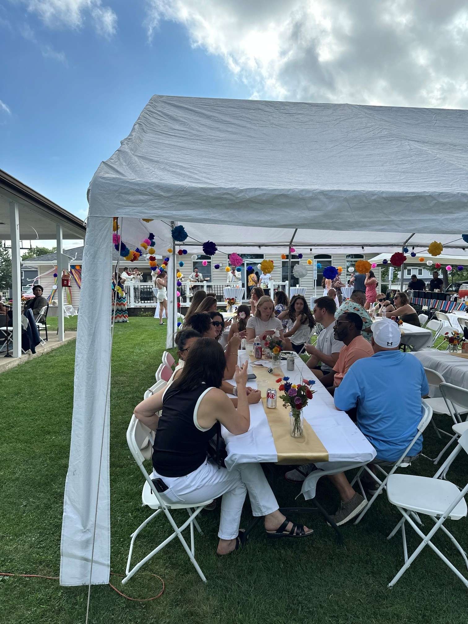 a group of people sitting at tables under a white tent