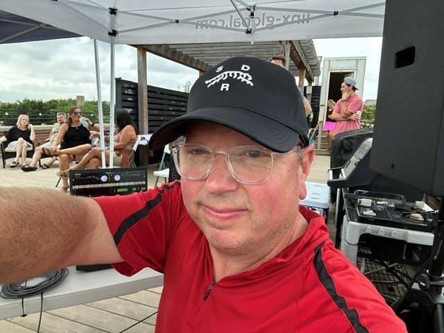 a man in a red hat is taking a selfie at an outdoor event